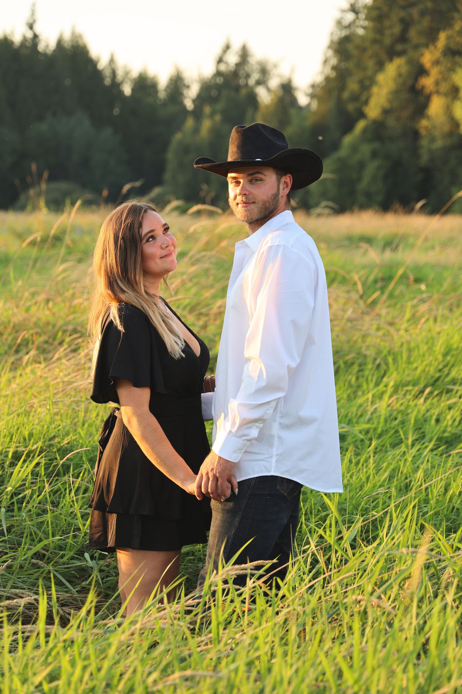 Couple in contrasting black and white outfits pose in tall summer grass.