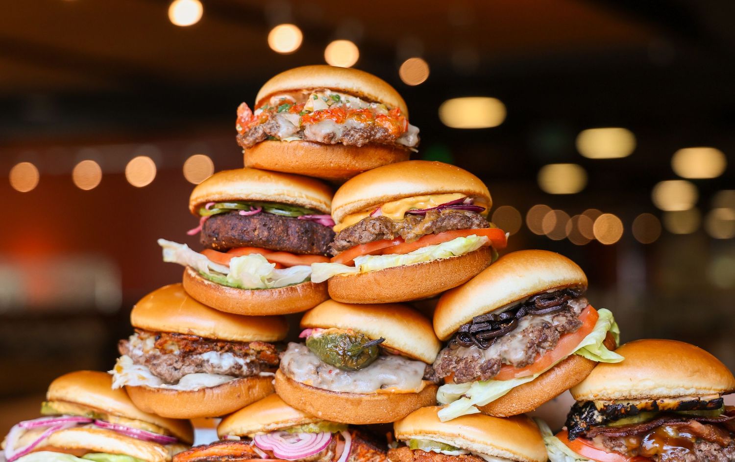 Row of juicy cheeseburgers with melted cheese and toppings lined up on display.