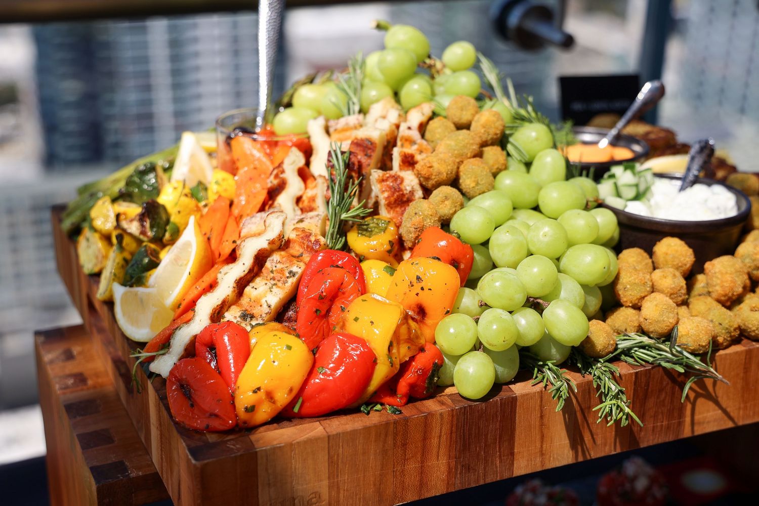 Fresh fruit and vegetable platter featuring grapes, tomatoes, and various produce on a wooden serving board.