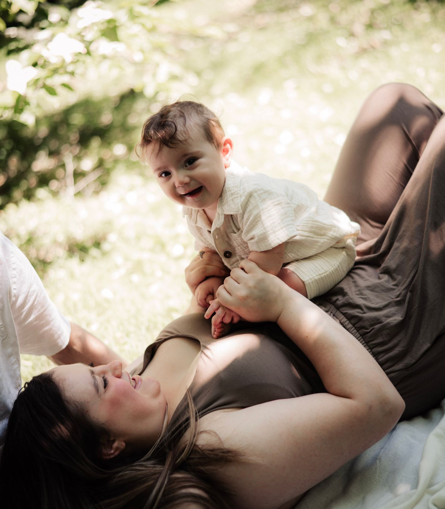 A tender moment of family bonding and laughter shared outdoors in natural sunlight.