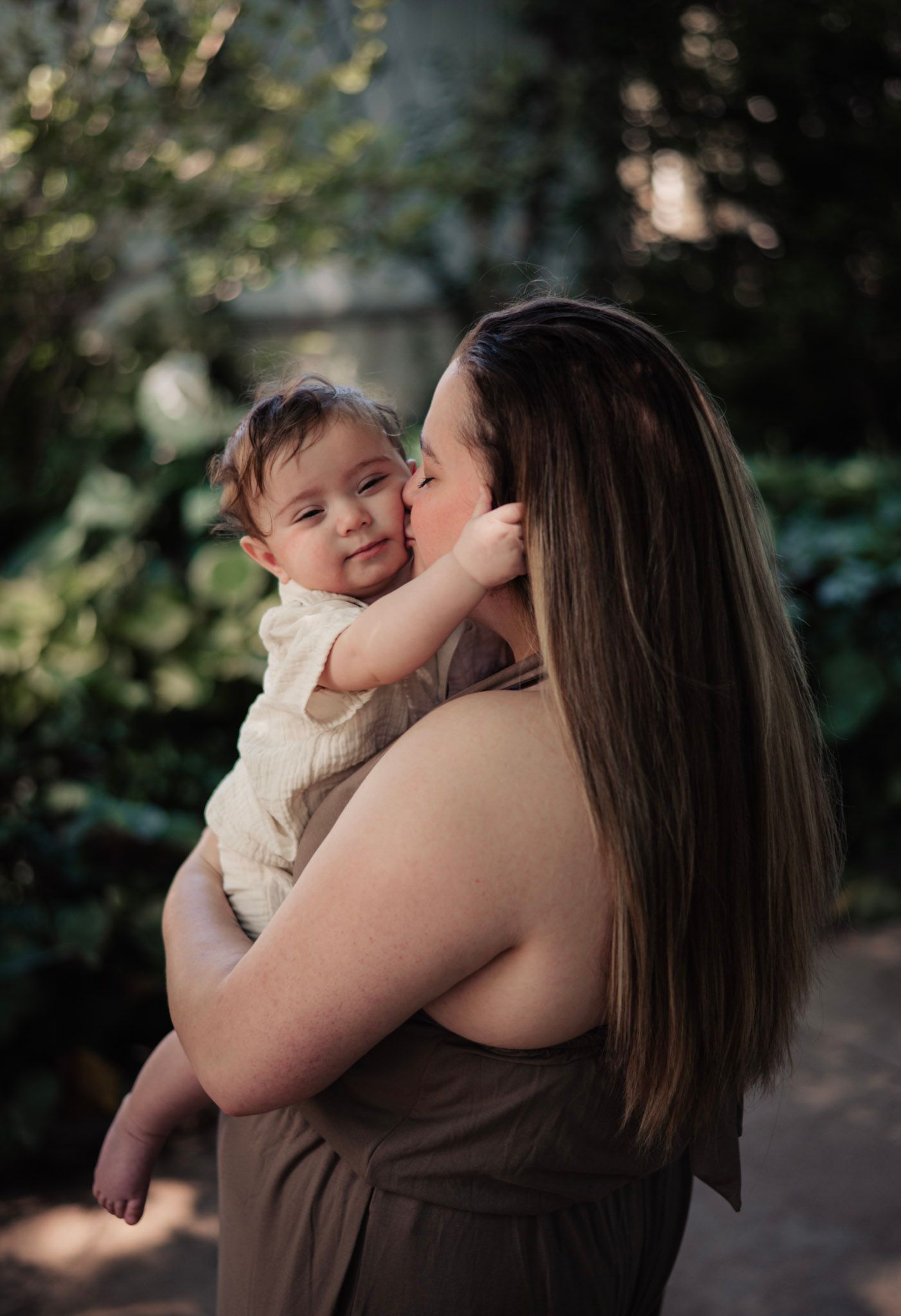 An intimate mother-child moment captured in warm lighting outdoors.
