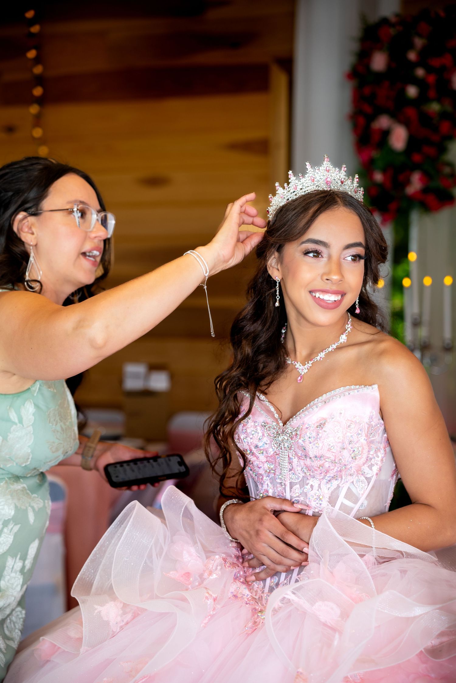 A person wearing a pink and white quinceañera dress with a tiara dances during a celebration.