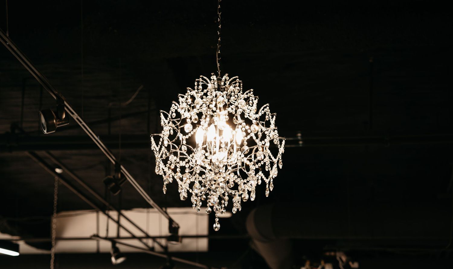 An elegant crystal chandelier with cascading prisms illuminates a dark space with warm glowing light.