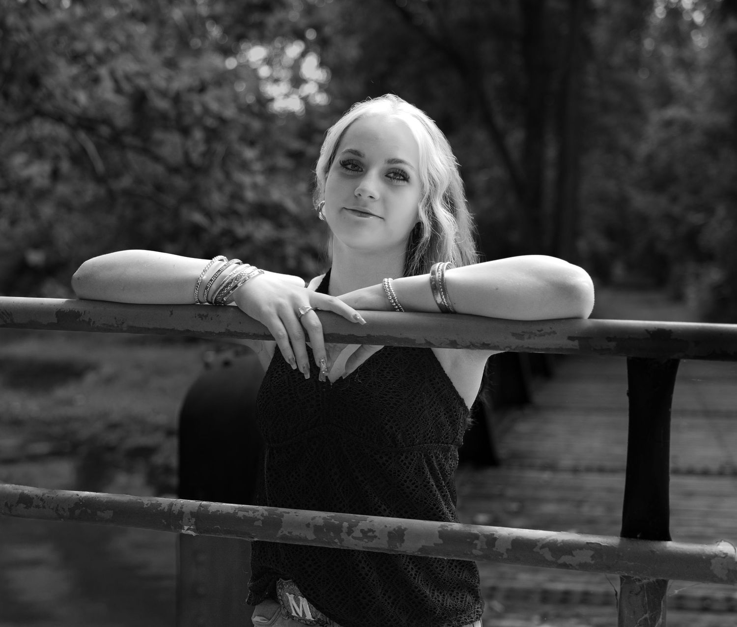 A person leans thoughtfully against a wooden railing in a series of black and white artistic outdoor portraits.
