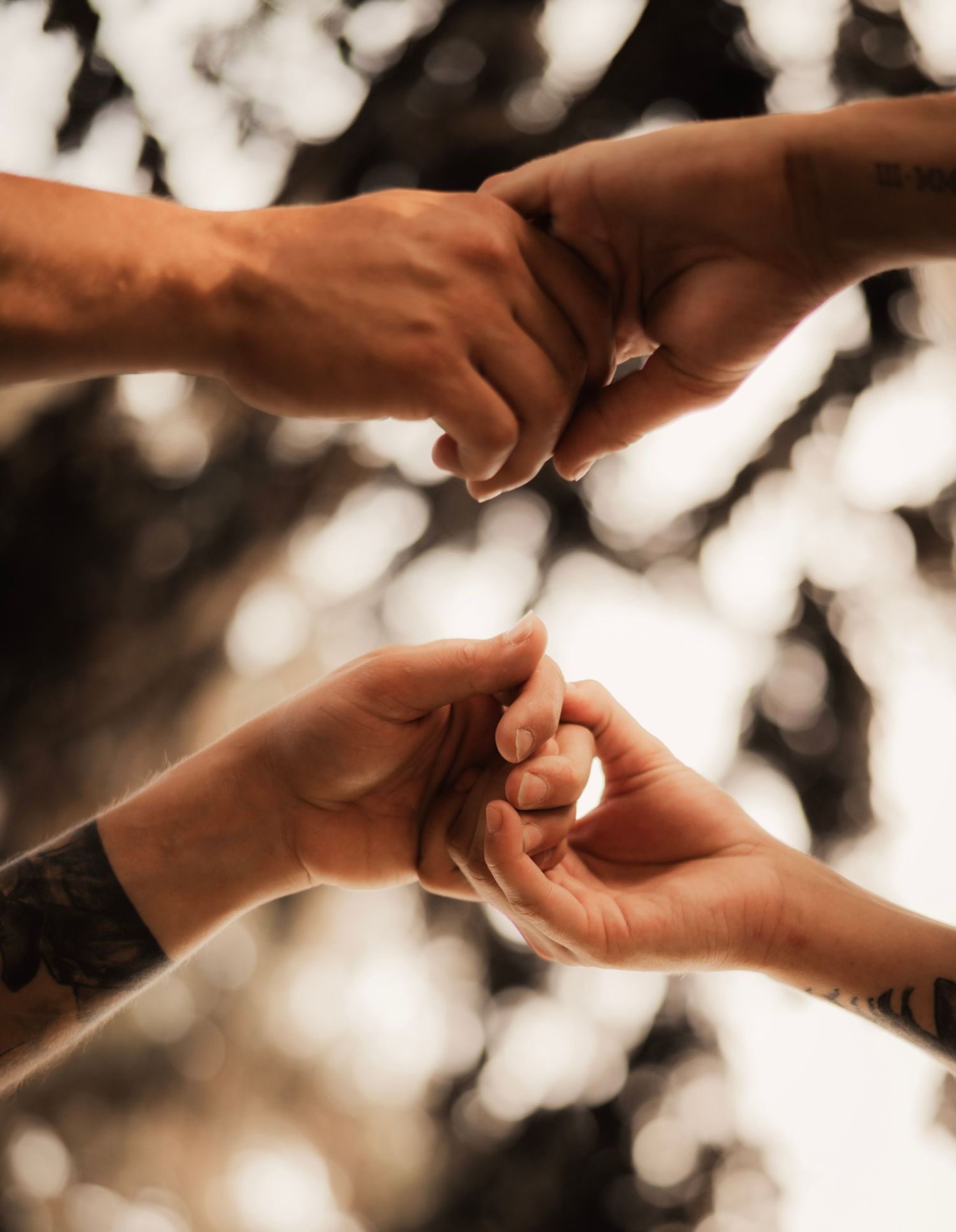 Hands gently exchanging wedding rings in soft focus with bokeh lighting effects in the background.