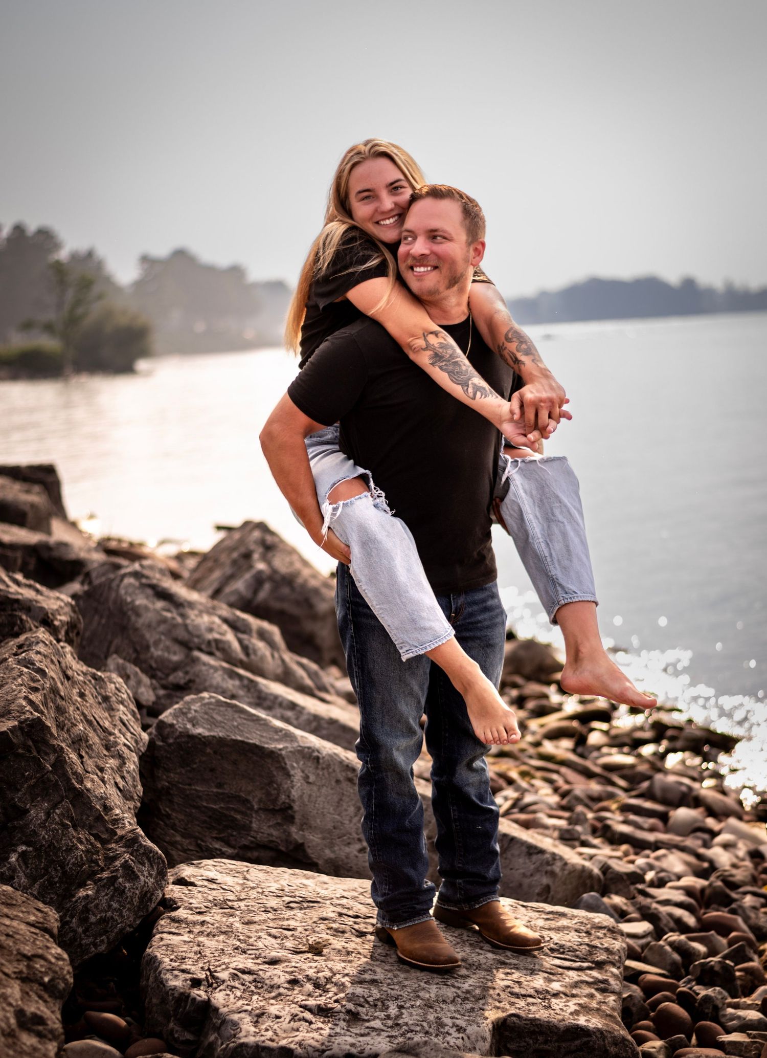 Couple sharing intimate moments on rocky beach shoreline during sunset photoshoot.