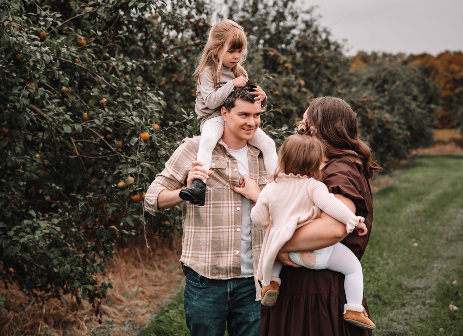 Family enjoying a tender moment together outdoors in an autumn orchard setting.