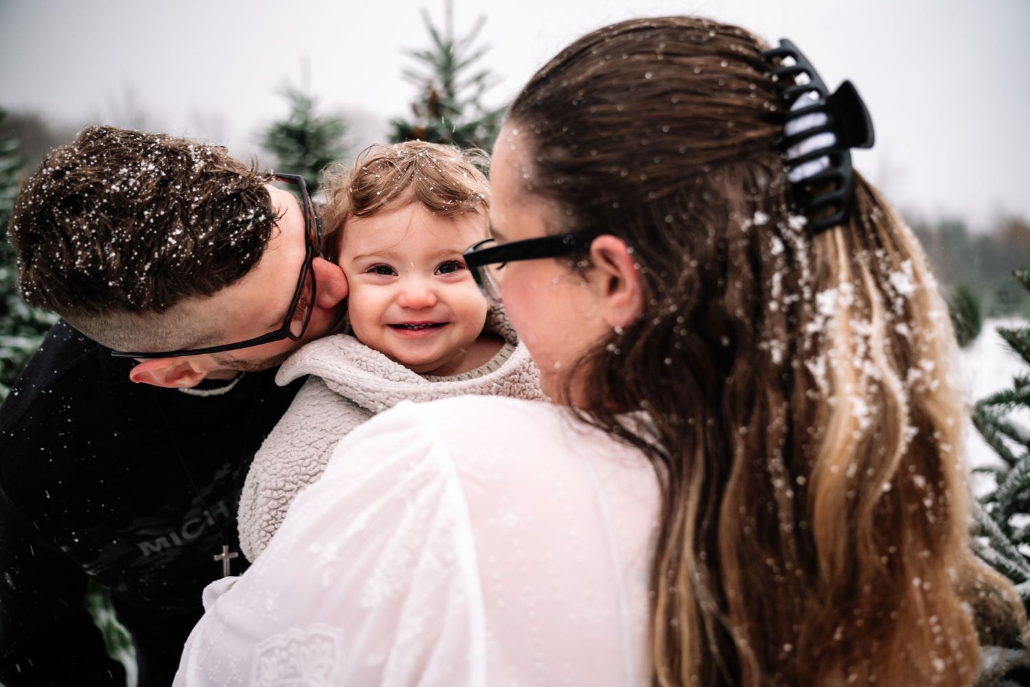 A tender moment between family members embracing outdoors in winter with snow visible in the background.