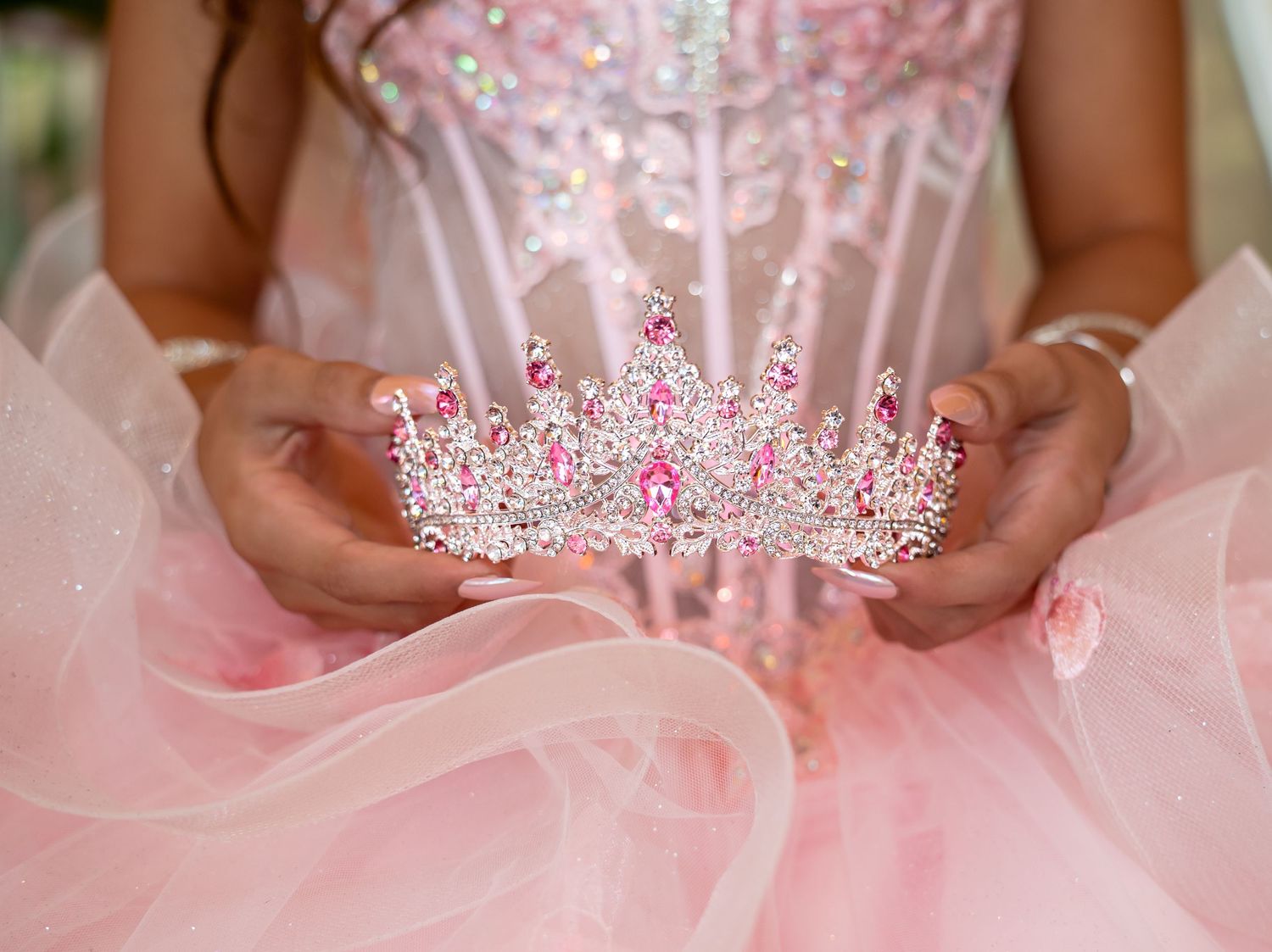 A delicate pink tulle dress with crystal tiara and floral details is showcased in multiple close-up shots.