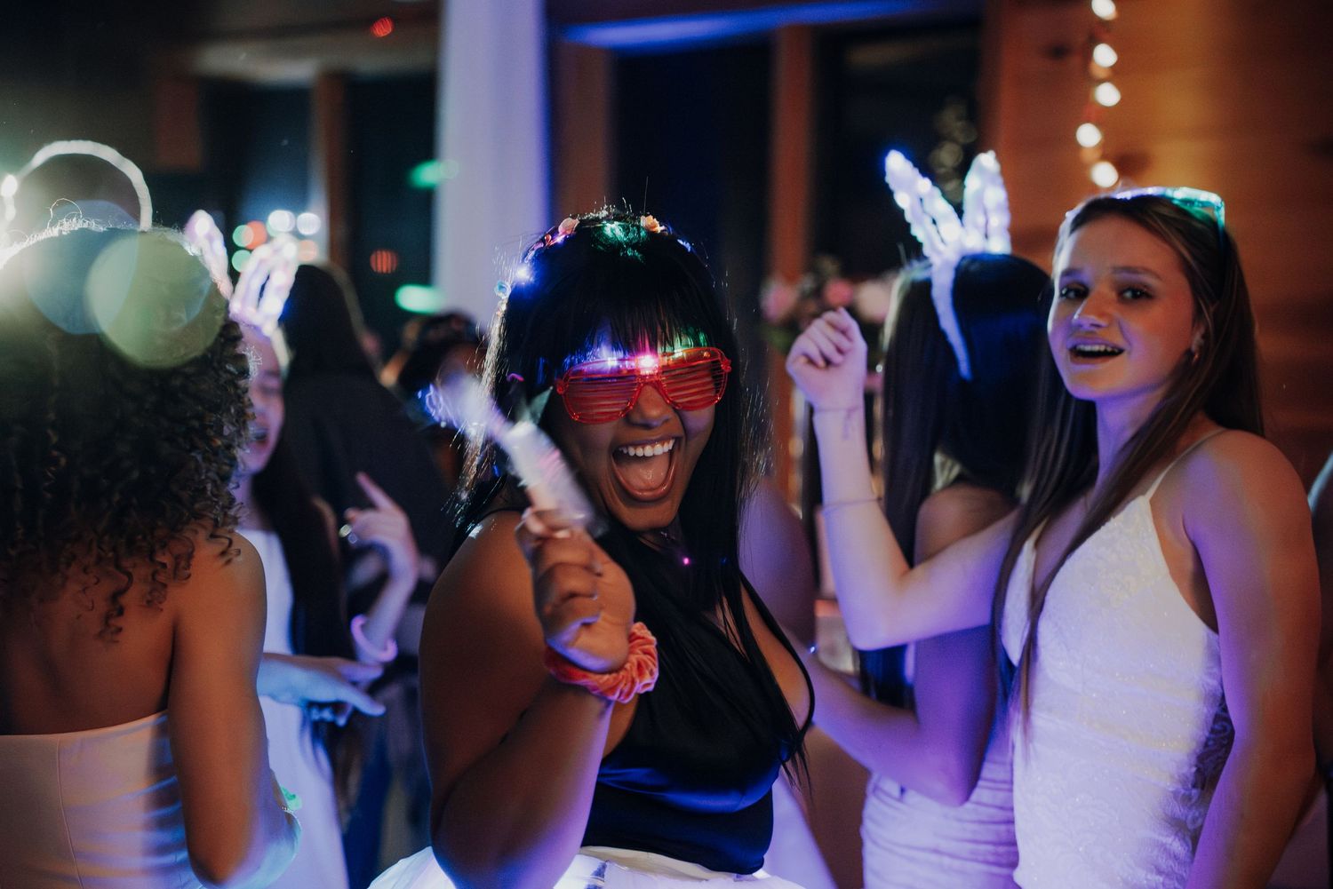 People dancing and having fun at a nightclub party with colorful lighting and festive atmosphere.