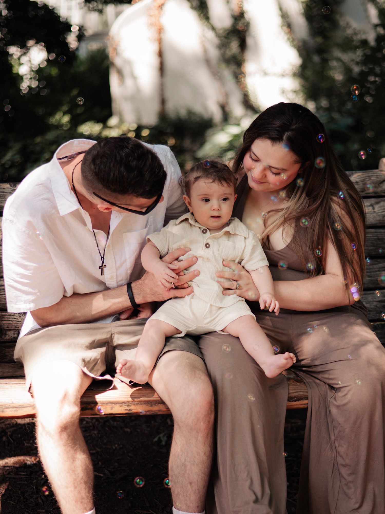 Family of three smiling and holding hands in forest setting