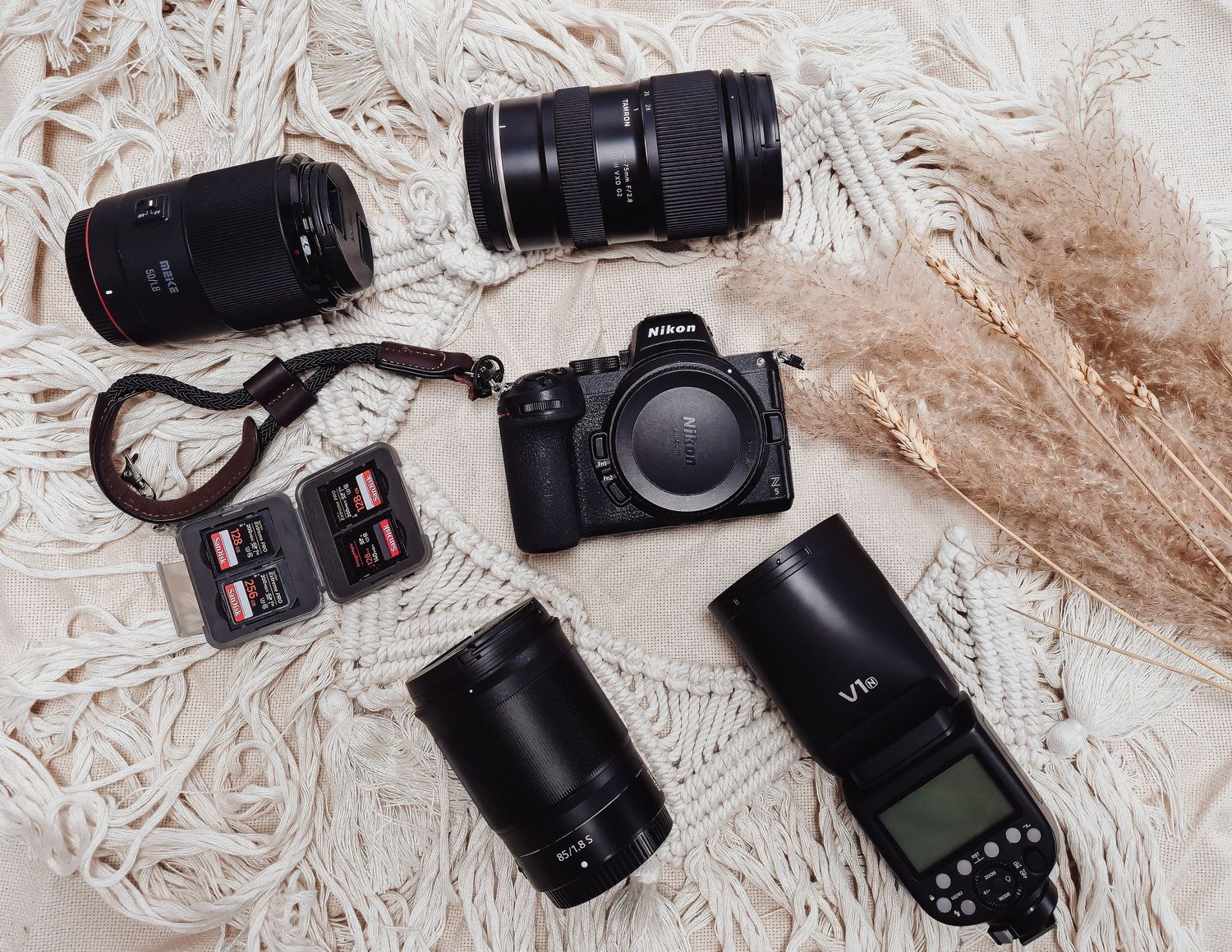 Professional camera equipment including lenses and camera body arranged on a white textured surface with neutral tones.