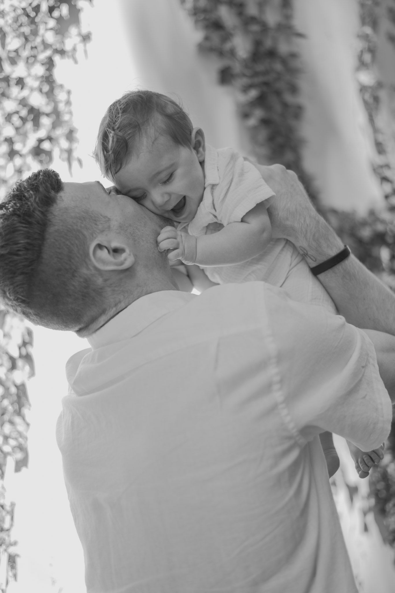 Black and white portrait of tender parenting moment with playful expressions.