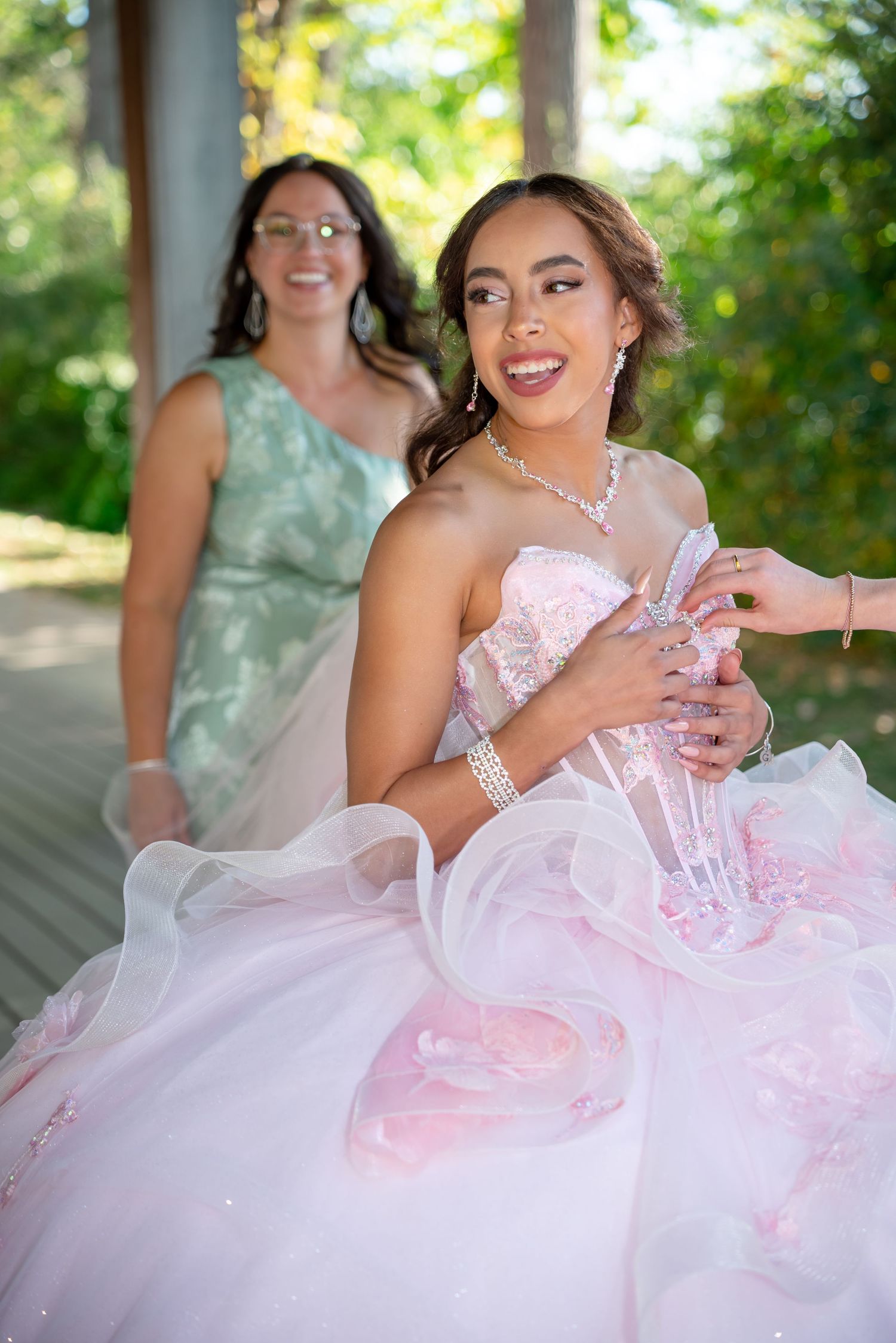 A joyful celebration in a garden setting with someone wearing a flowing pink and white formal gown.
