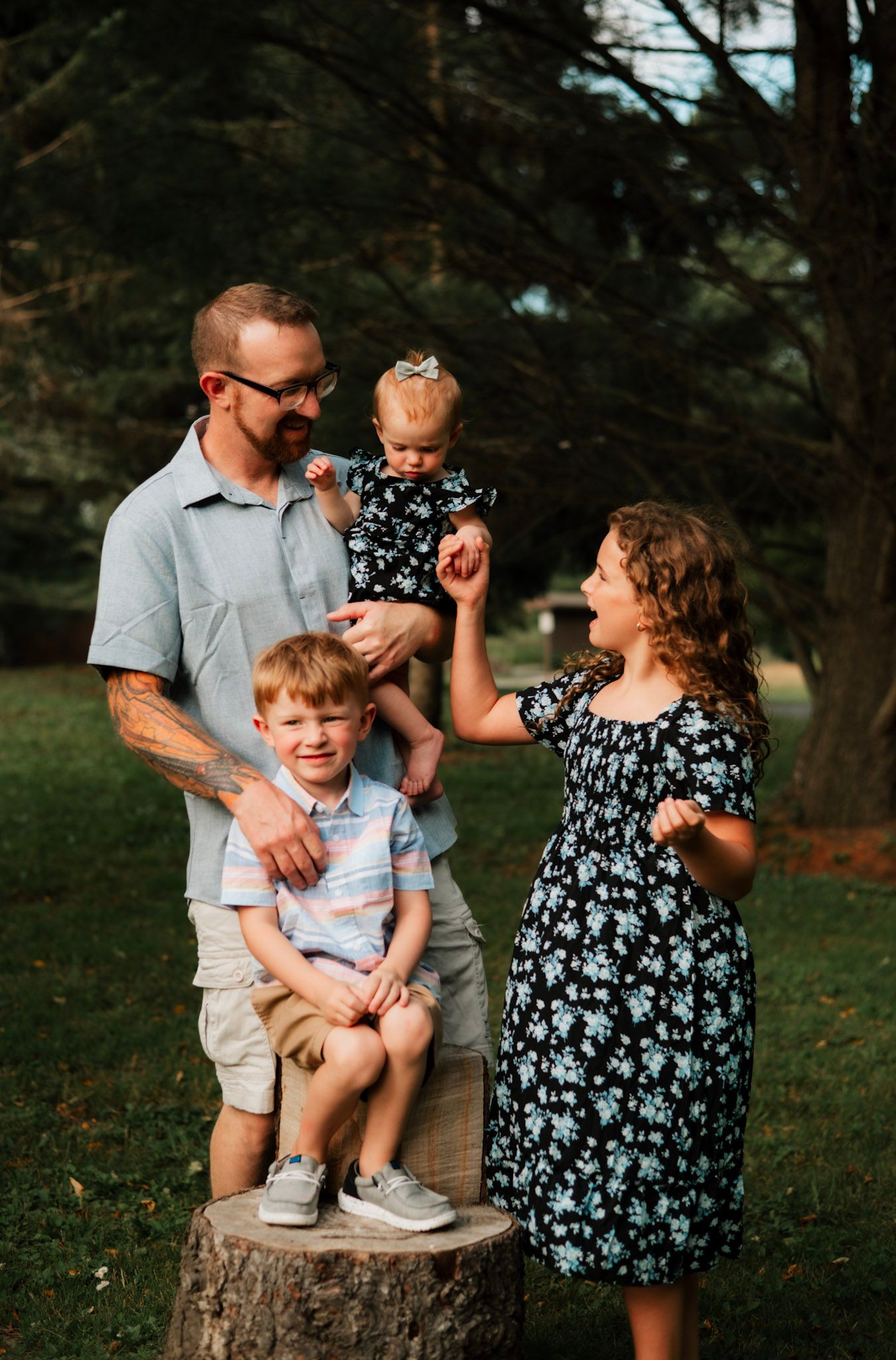 A lovely family shares playful moments together while posing on a tree stump in a natural outdoor setting.