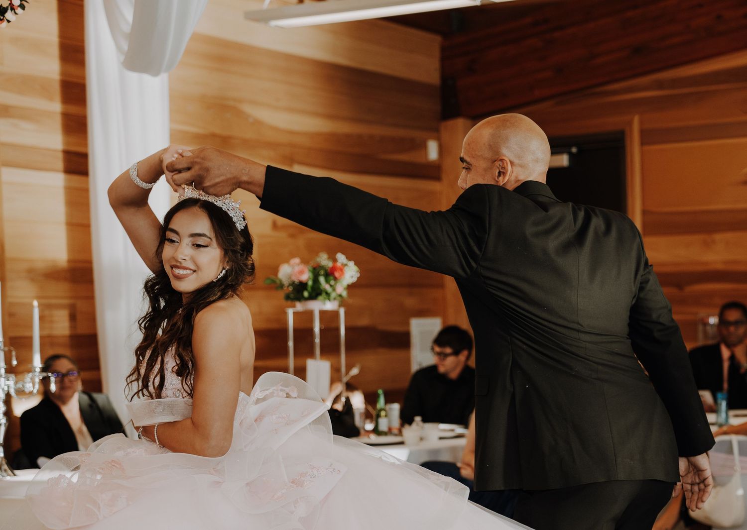 Joyful wedding party celebrates with sparklers outside a rustic wooden cabin at night.