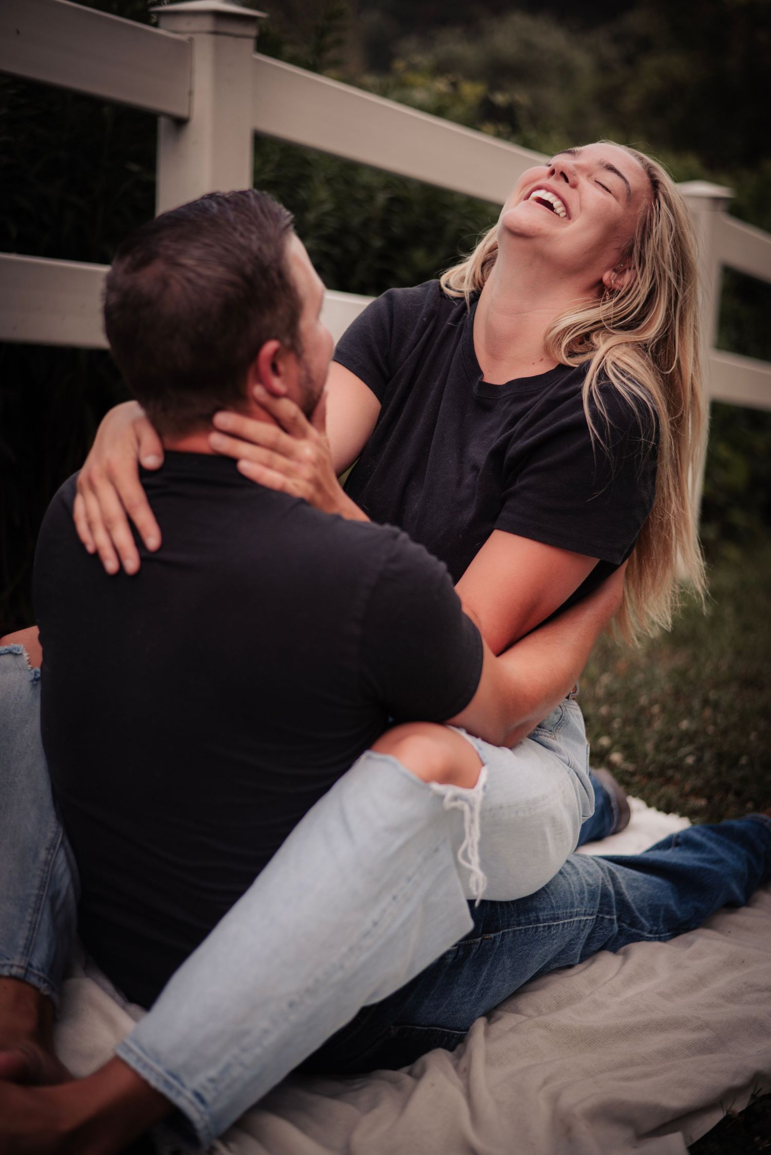 A couple shares a joyful, intimate moment while sitting together outdoors.