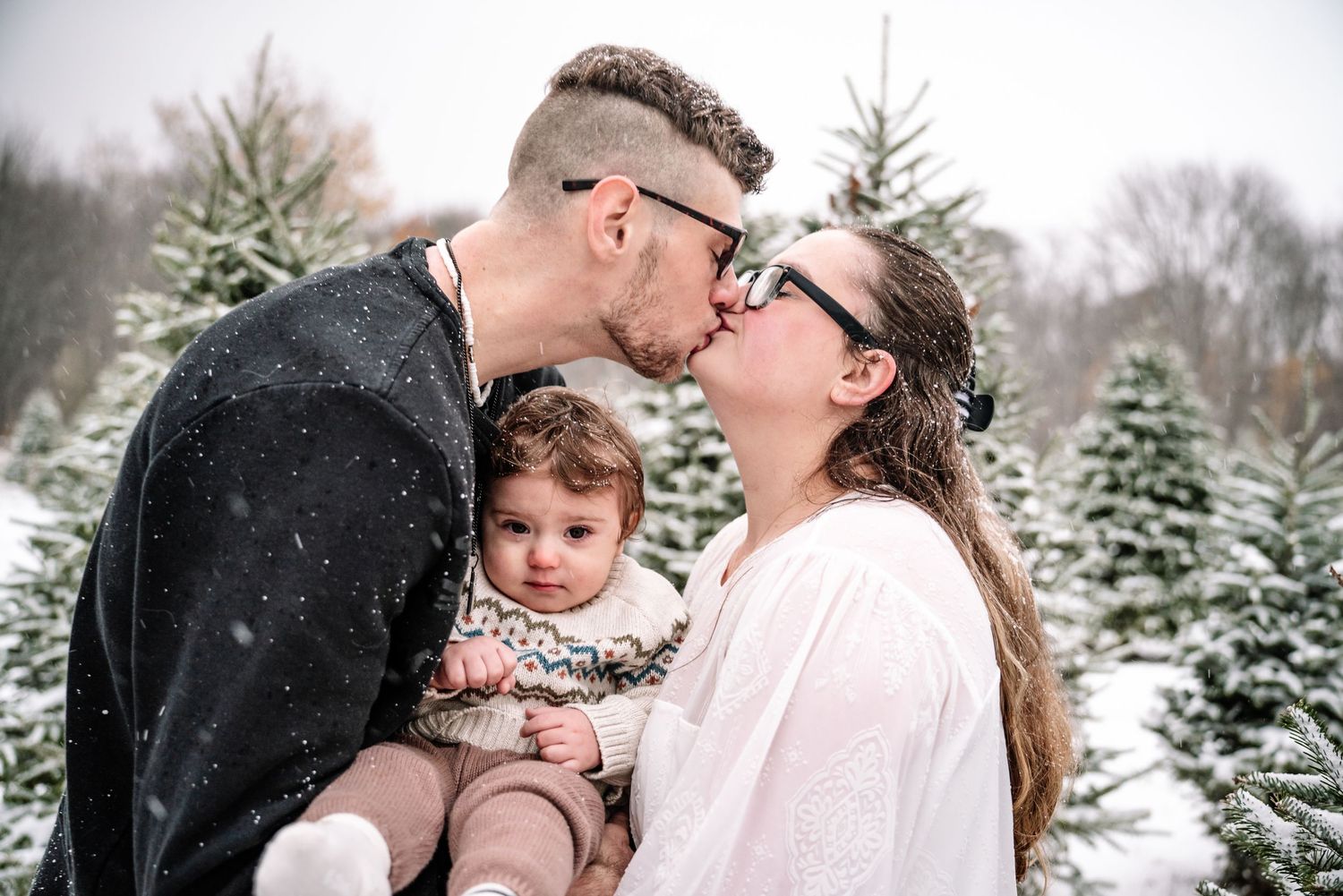 A winter engagement photoshoot in a snow-covered evergreen forest with romantic poses and tender moments.