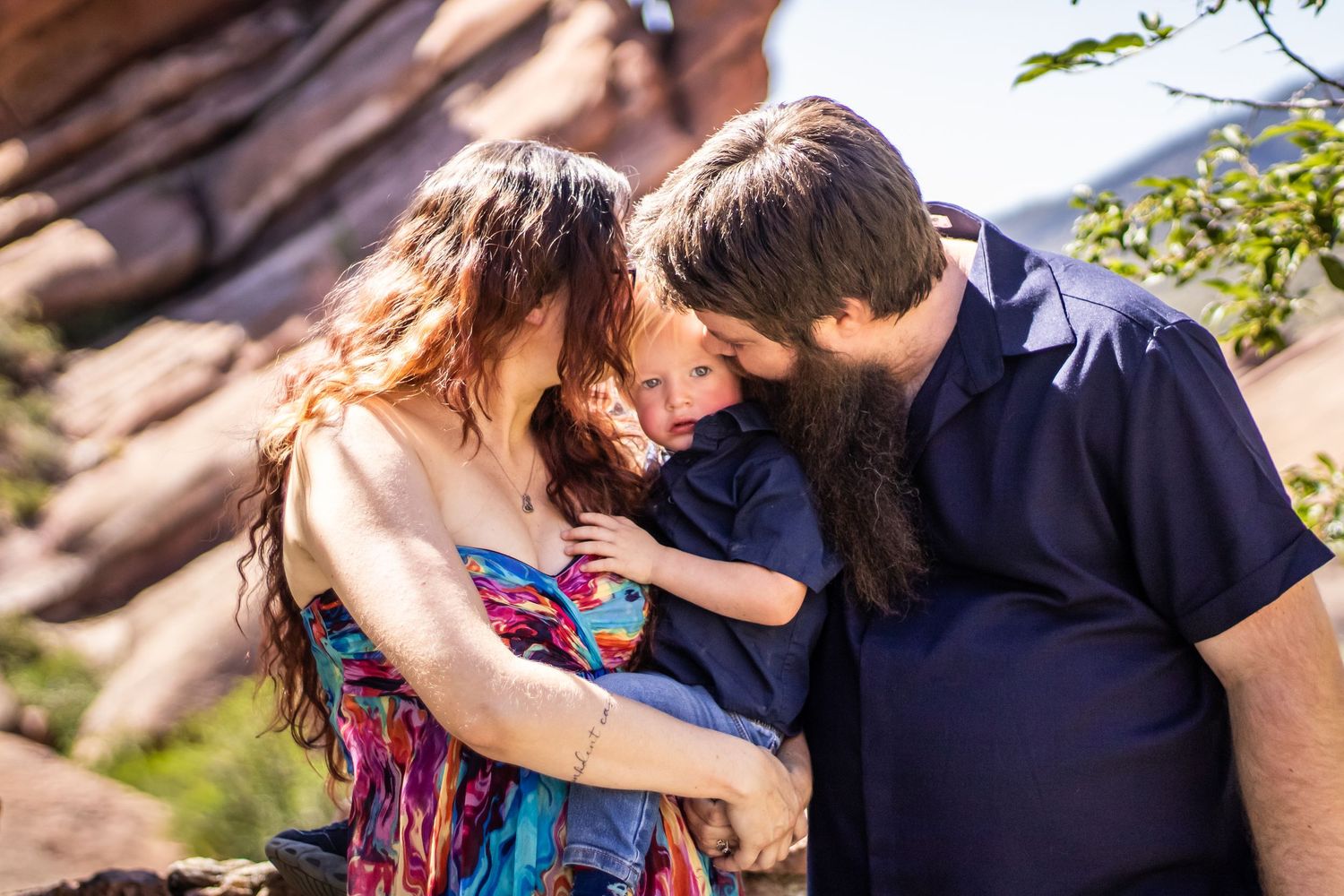 Romantic couple embraces and kisses in a scenic outdoor setting during a sunny afternoon.
