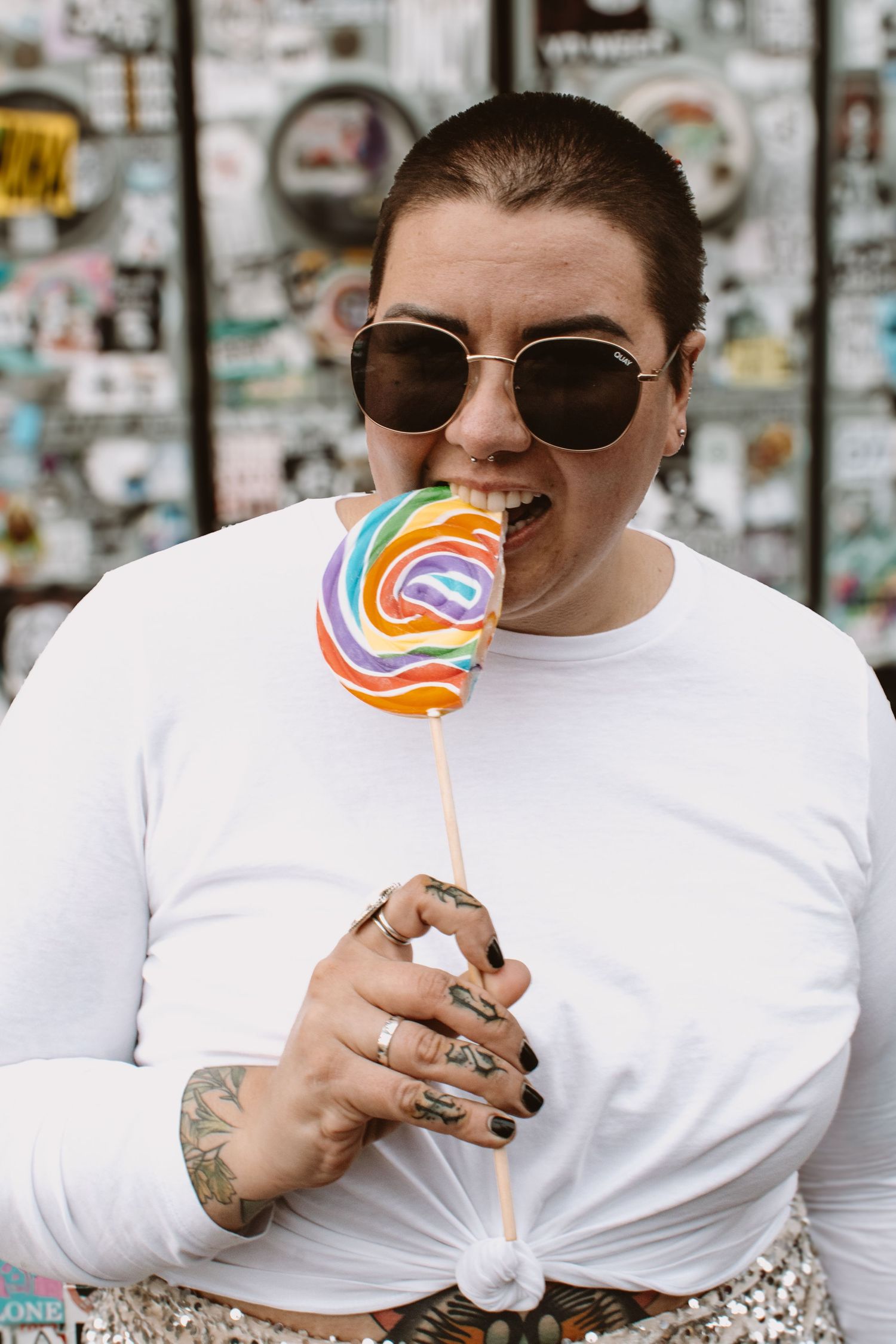 A person in sunglasses and white shirt enjoys a colorful lollipop in a series of progressive shots.