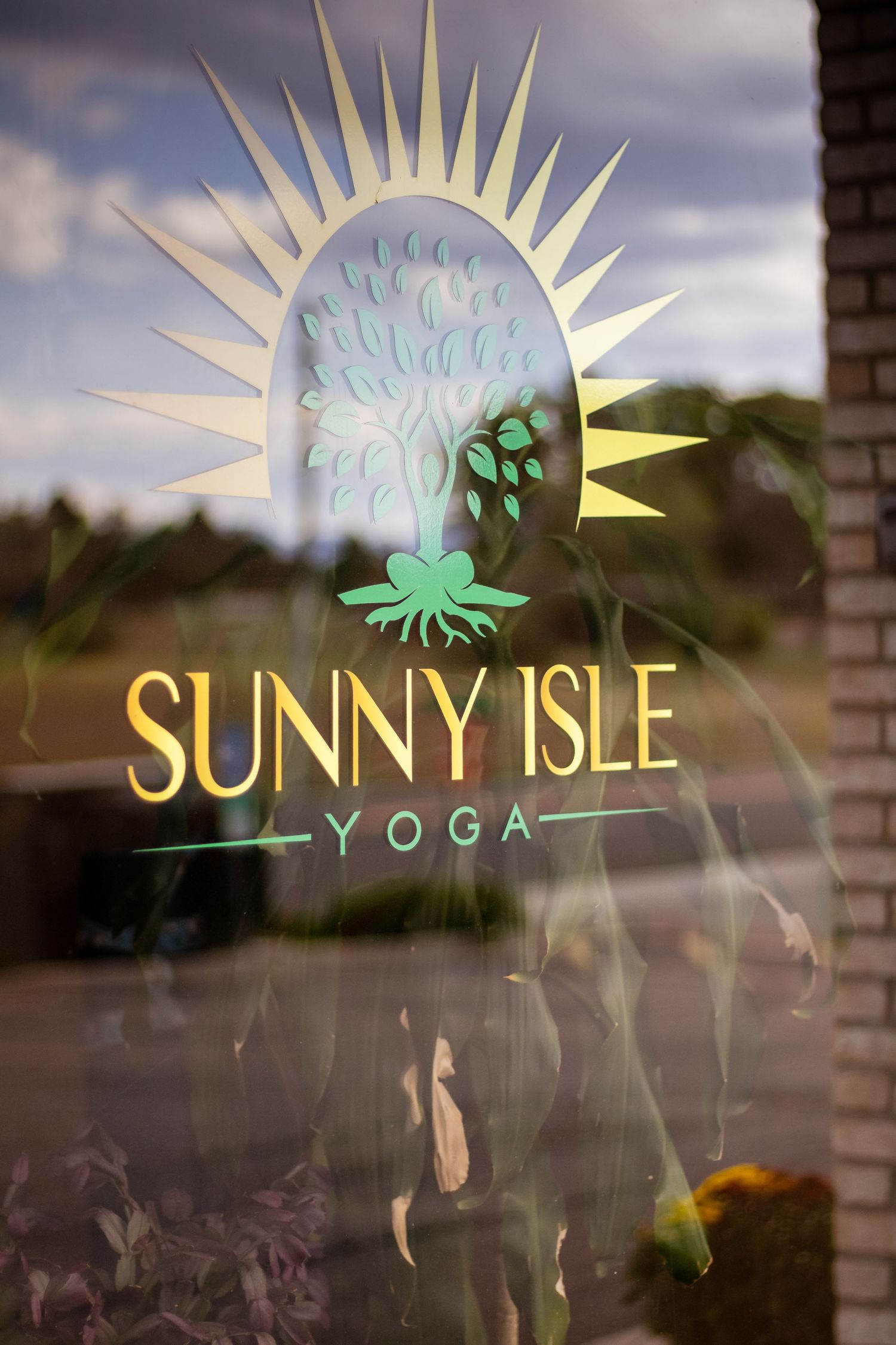 Sunny Isle logo design progression showing different iterations of a sun-themed brand identity on glass window displays.