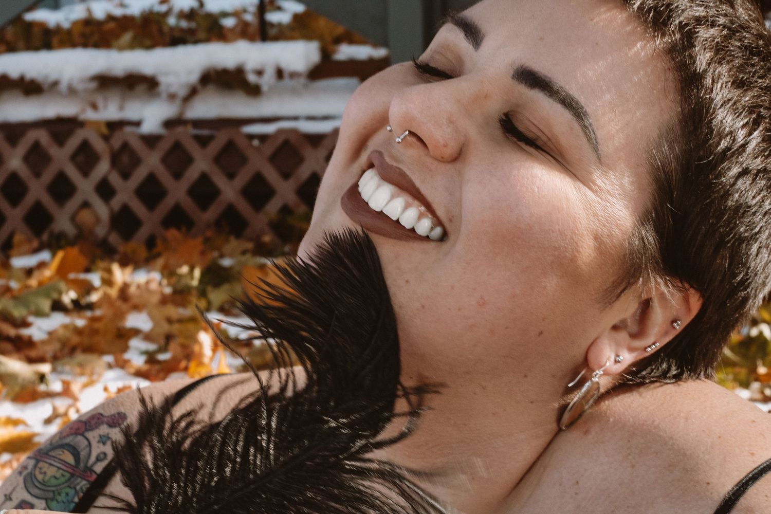 A joyful expression radiates warmth as sunlight illuminates natural features in an outdoor autumn setting.