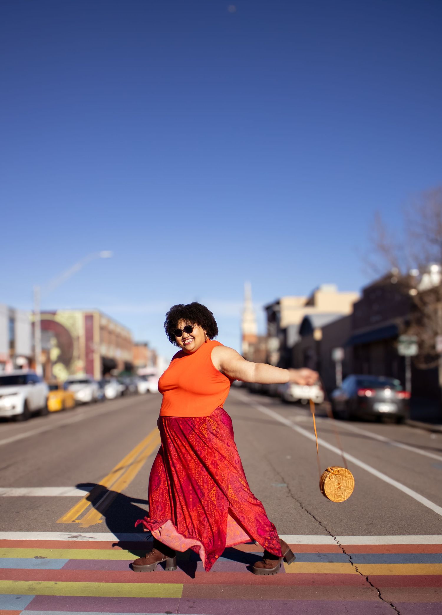 A sequence of photos showing a person in a bright orange top and red dress twirling in an empty parking lot.