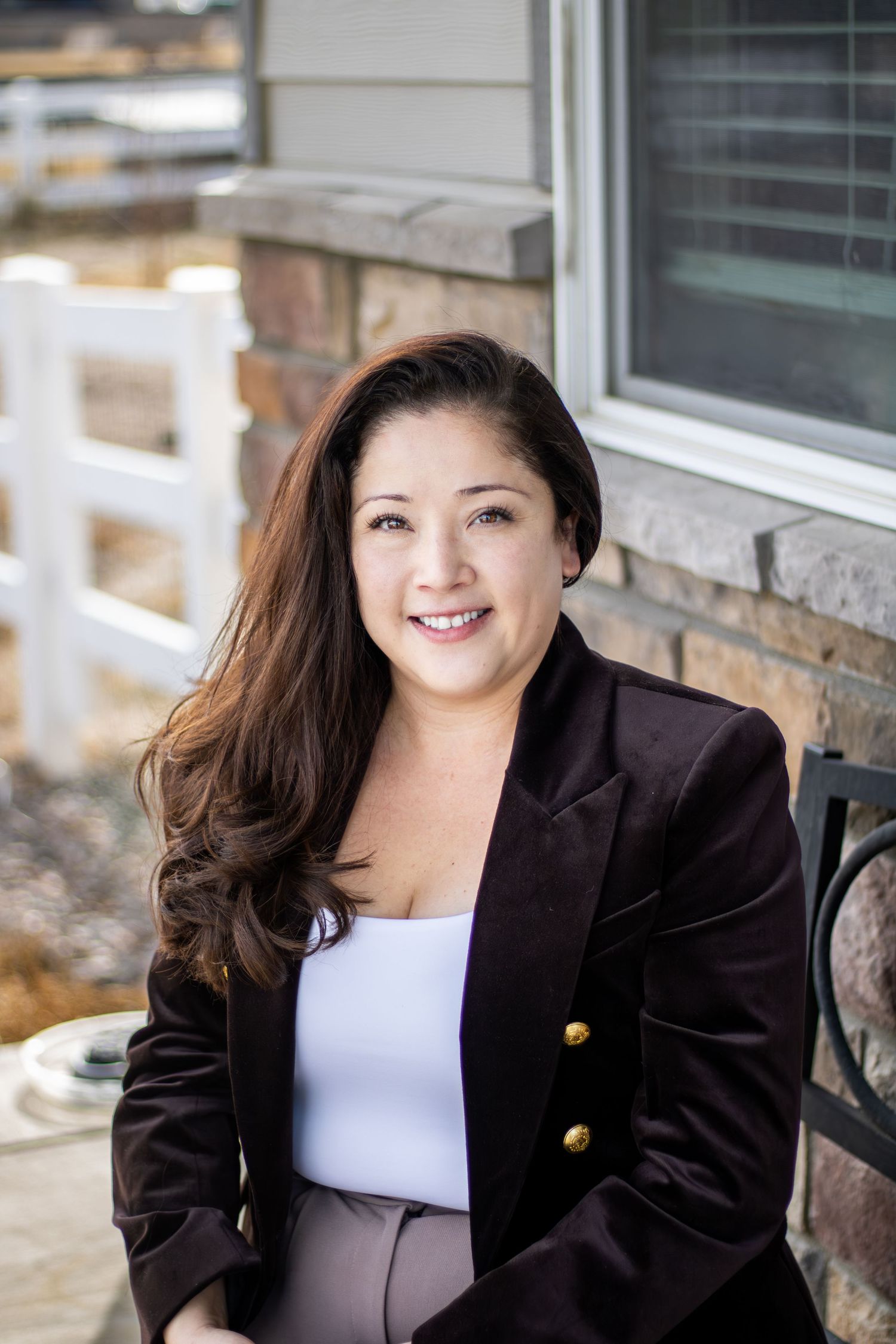 Professional headshot series showing a person in a black blazer and white top against a stone wall backdrop.