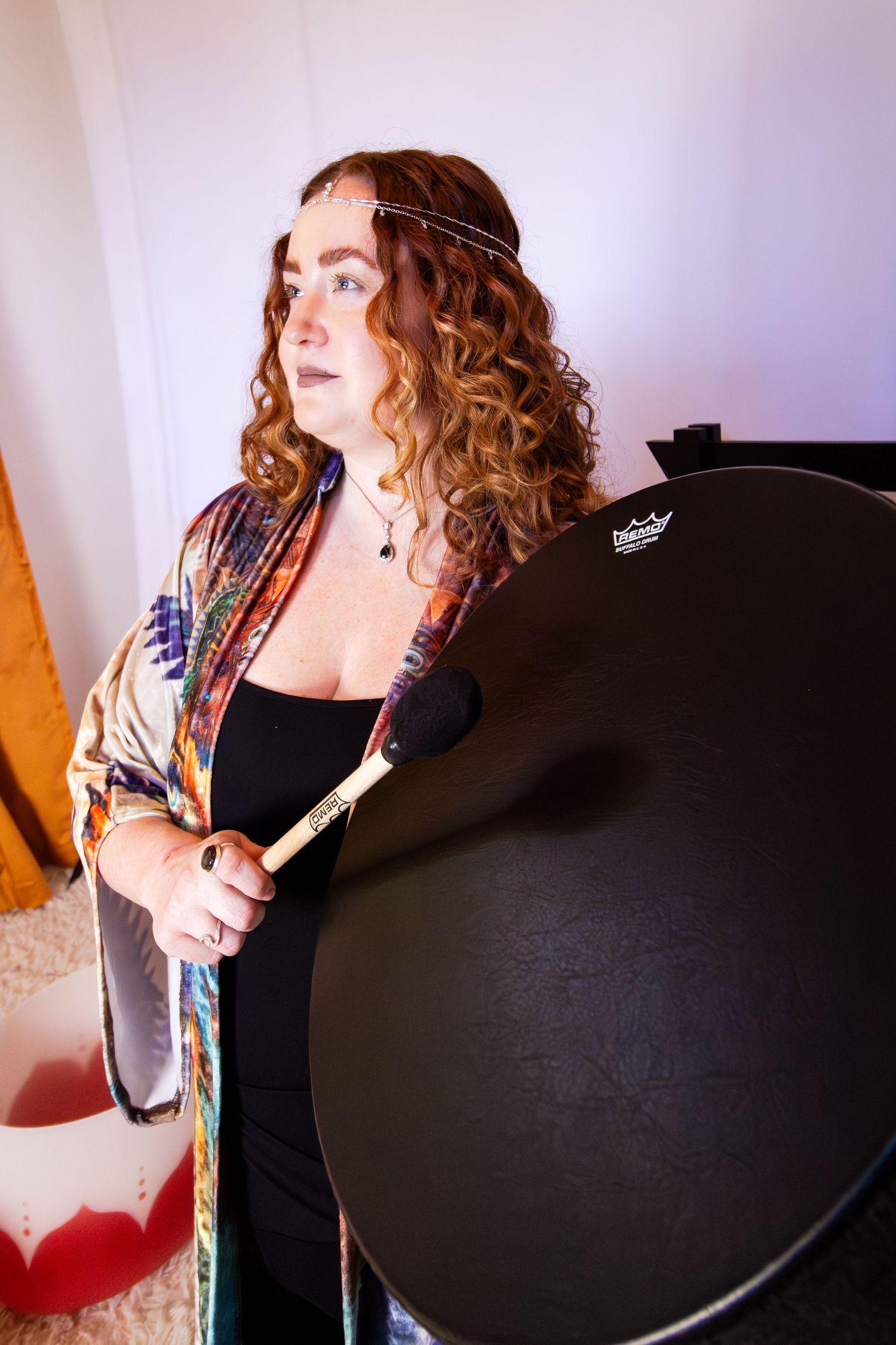 A person in black poses with a round dark object in a series of artistic indoor portraits.