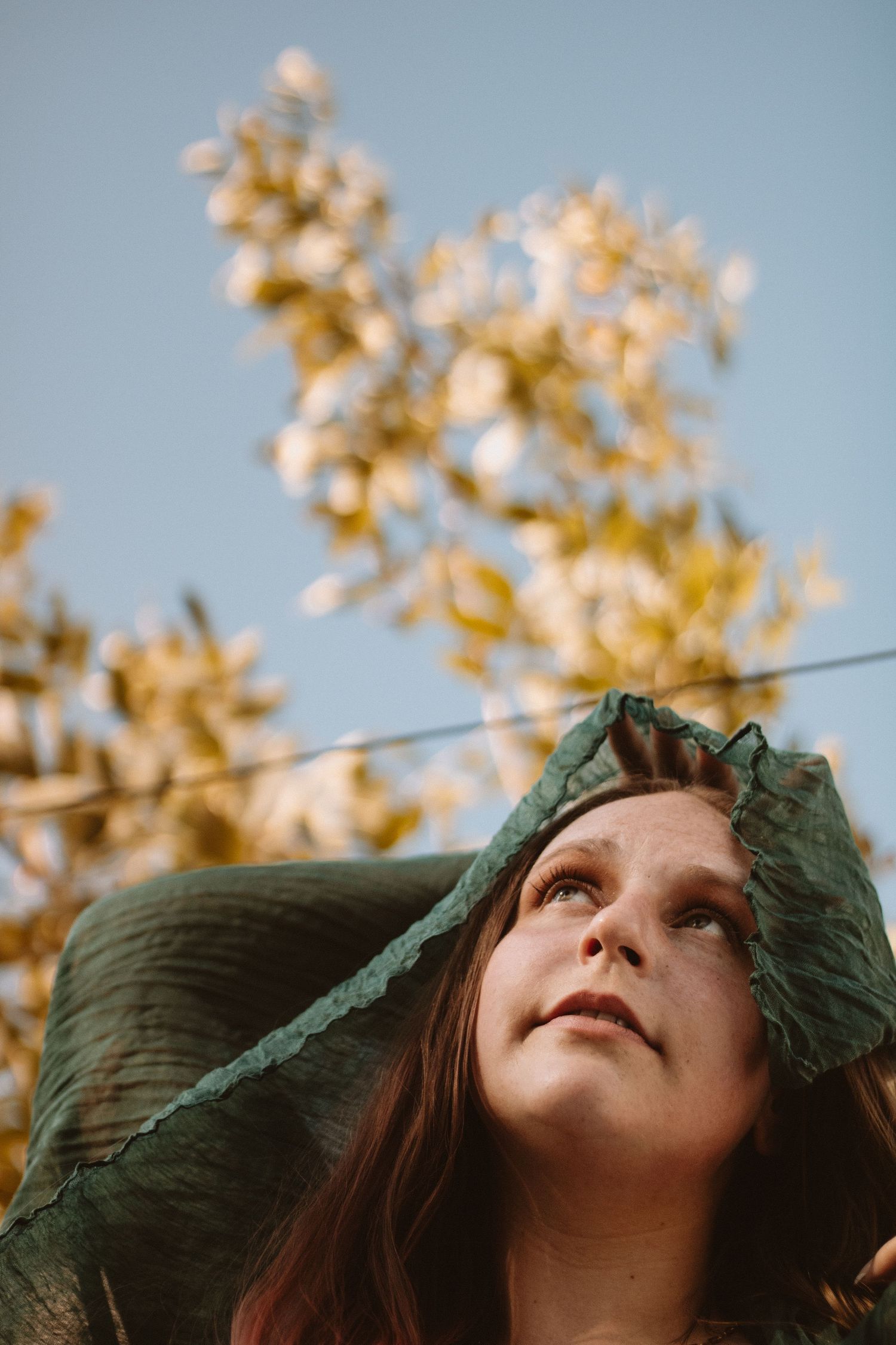 A person gazes upward at autumn leaves against a blue sky in a dreamy sequence of photos.