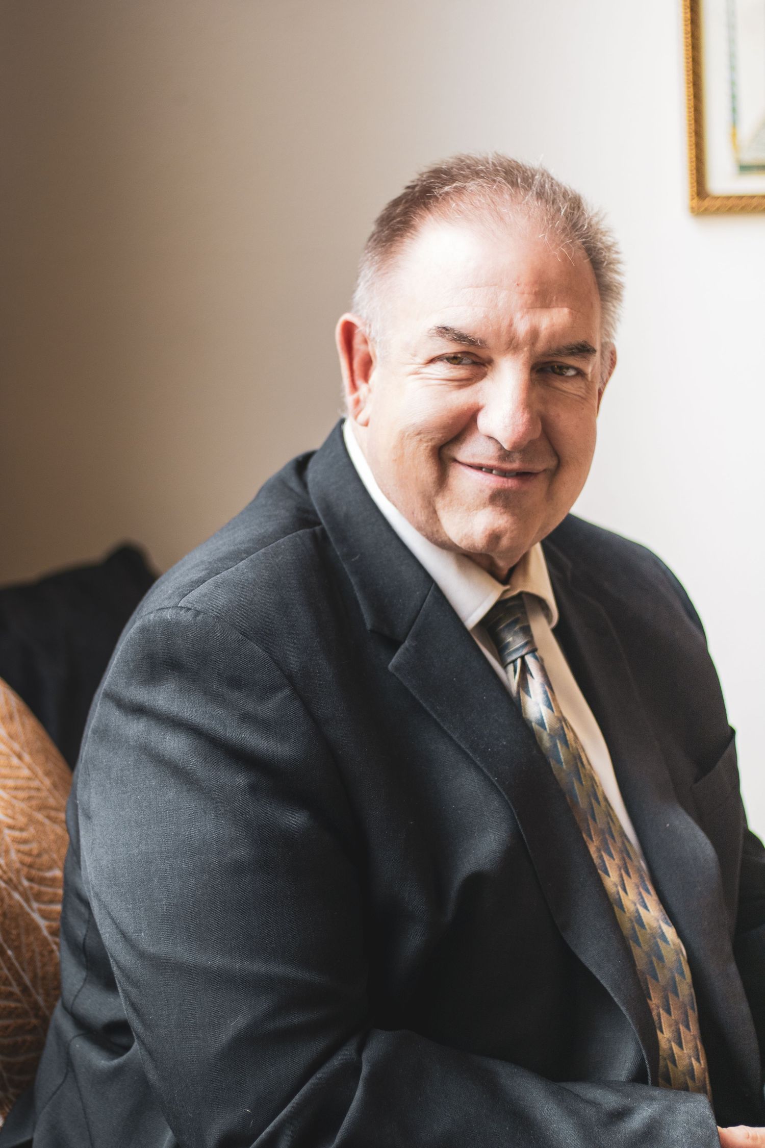 Professional portrait series showing a person in a dark business suit and tie smiling warmly against a light background.