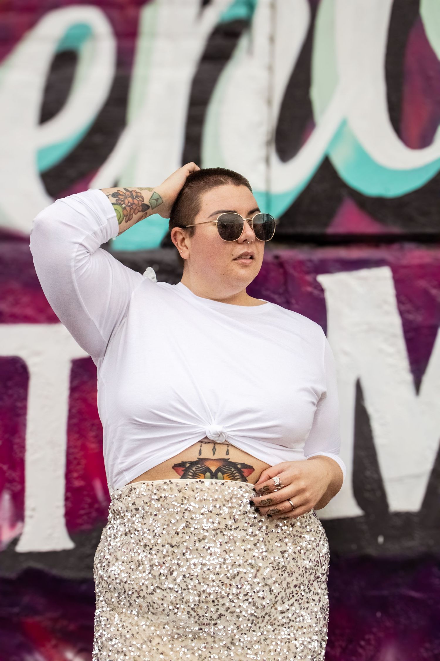 A person in a white top and sparkly skirt performs a dance routine on stage against a colorful backdrop.