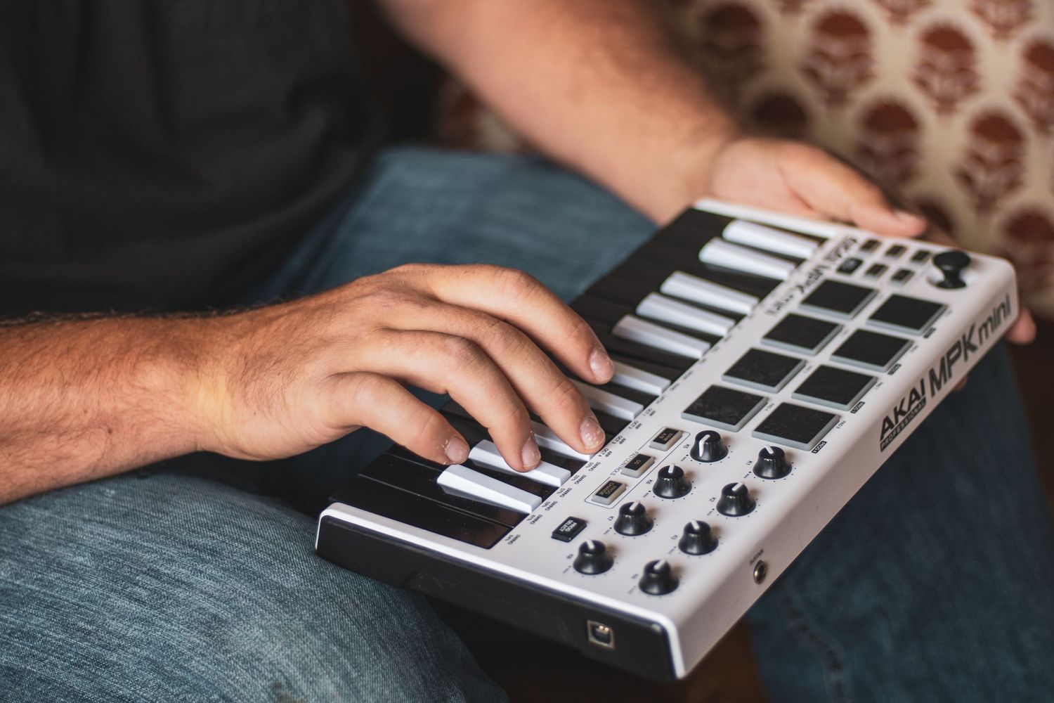 A sequence of close-up shots showing hands operating a MIDI keyboard controller with knobs and buttons.