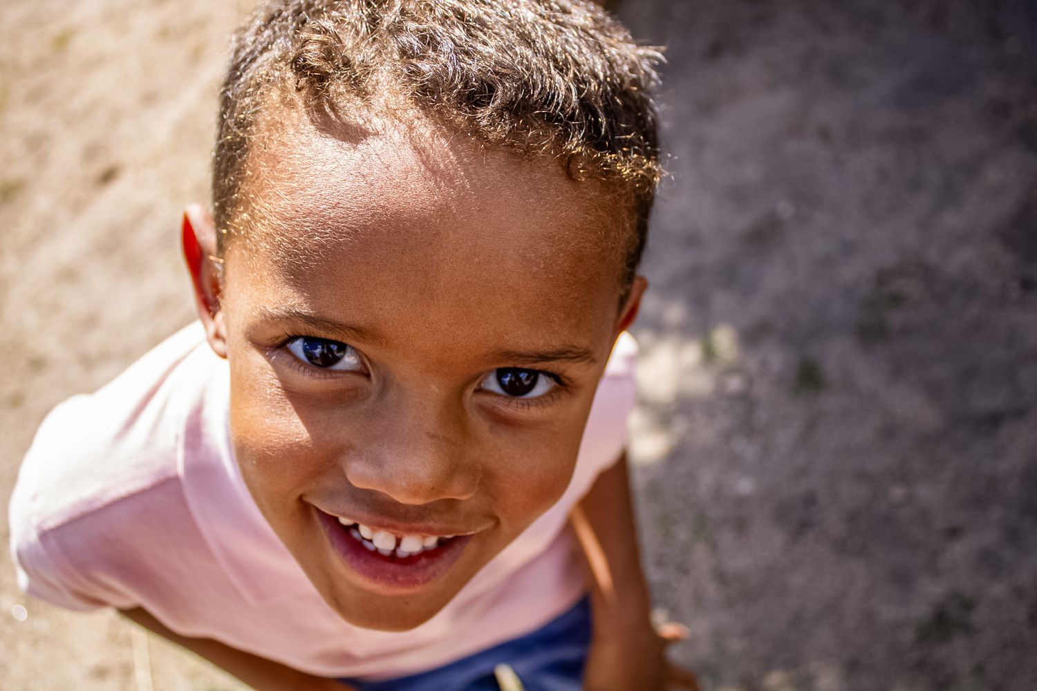 Close up portrait of a child smiling brightly against a blurred background.