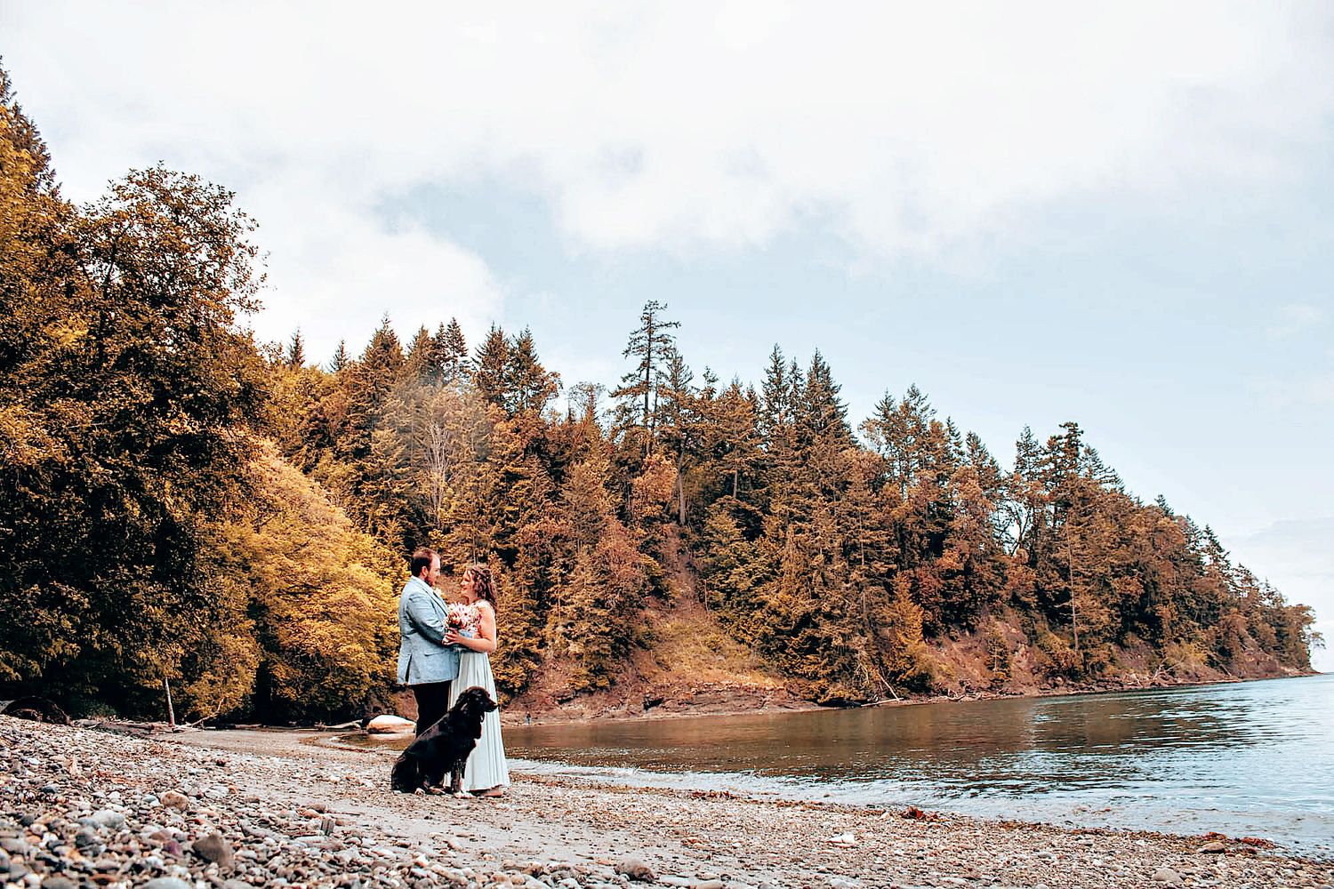 Scenic autumn beach wedding photos showing couple against backdrop of orange trees and Pacific Northwest coastline.