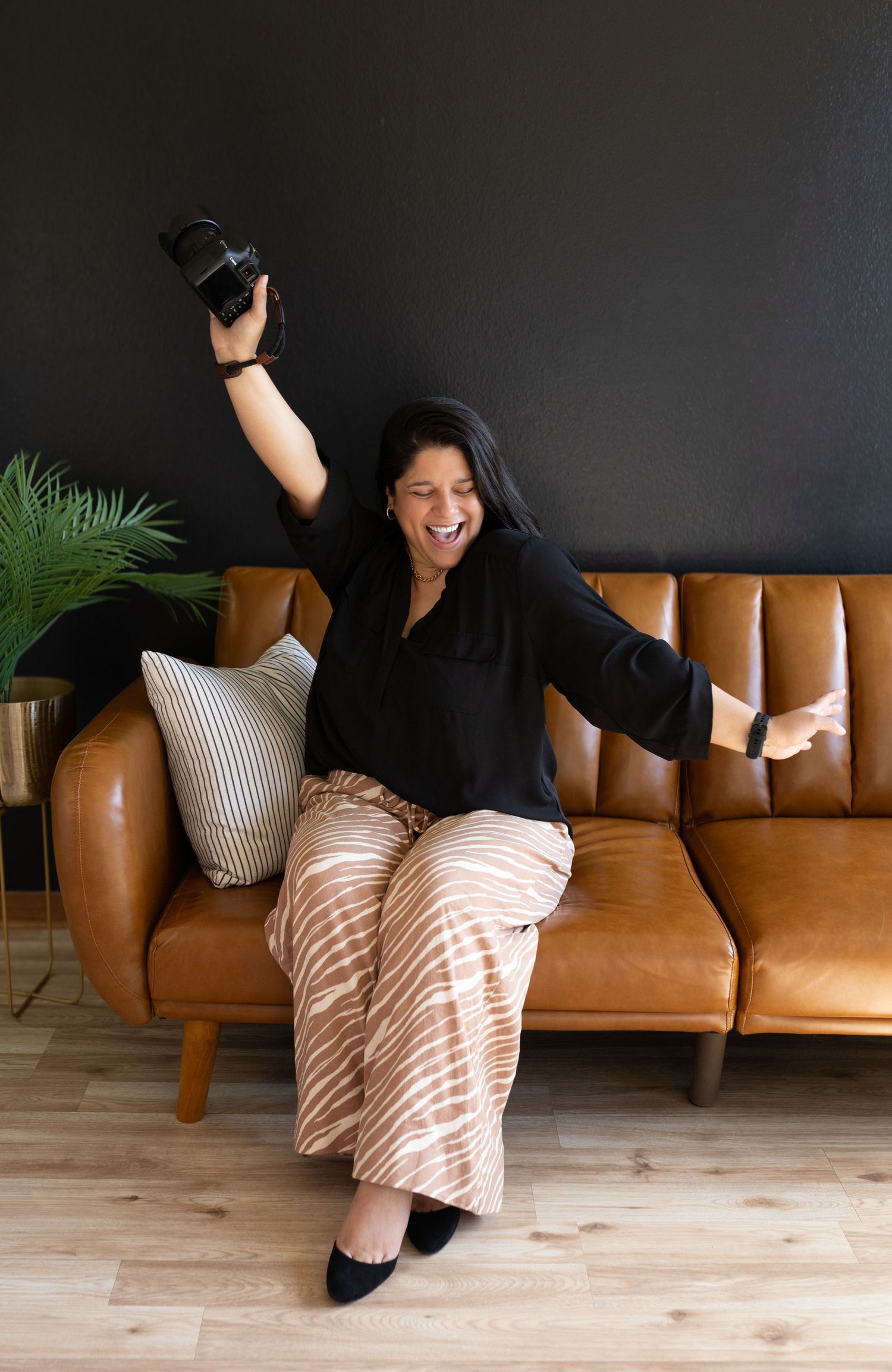 Casual lifestyle photo showing relaxed pose on modern brown leather sofa with throw pillows.