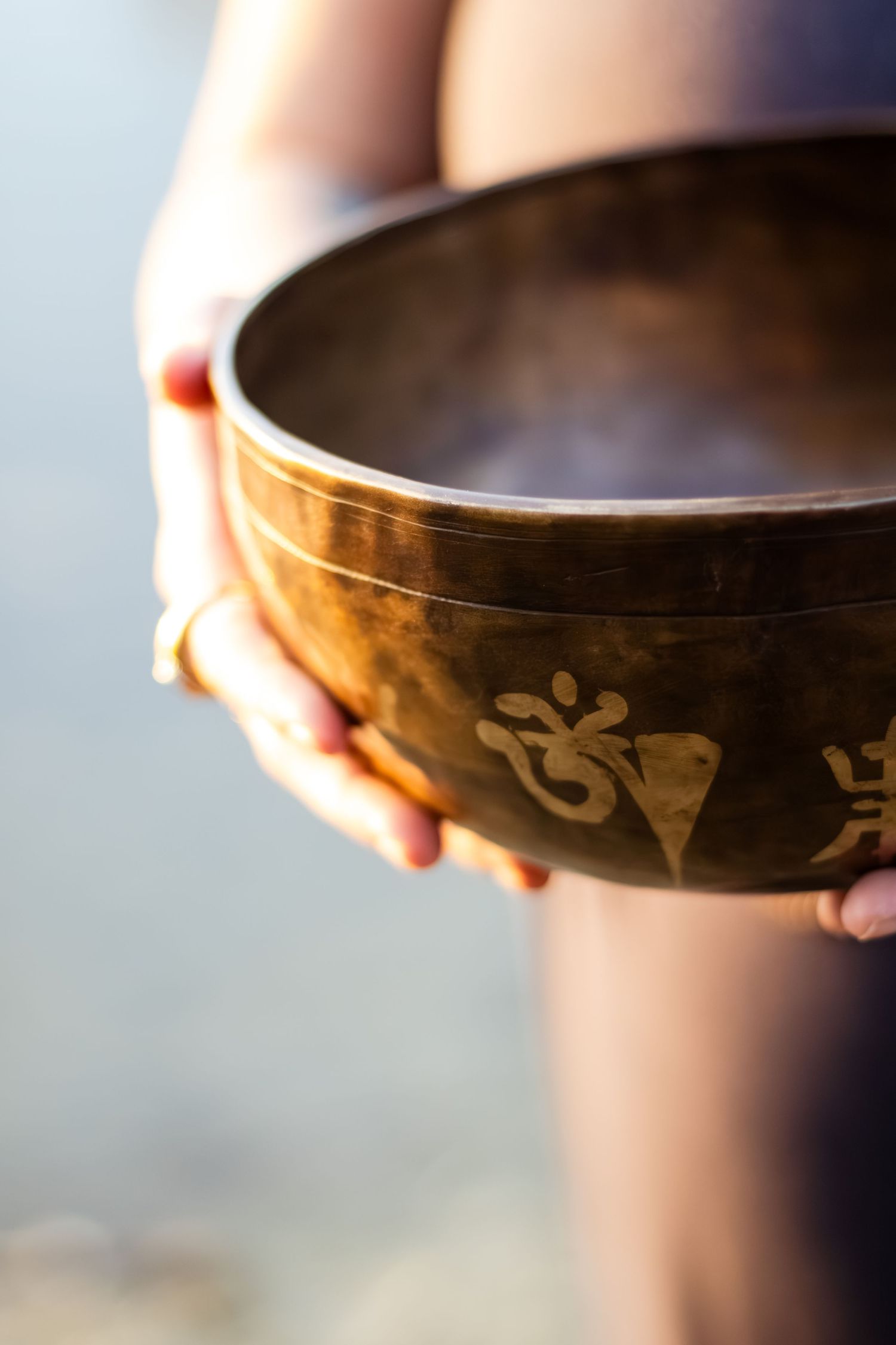 A close-up view of a decorative singing bowl with ornate patterns against a blurred background.