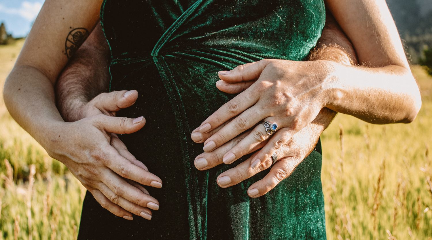 Close up detail shots of hands touching a green velvet dress in a golden wheat field at sunset.