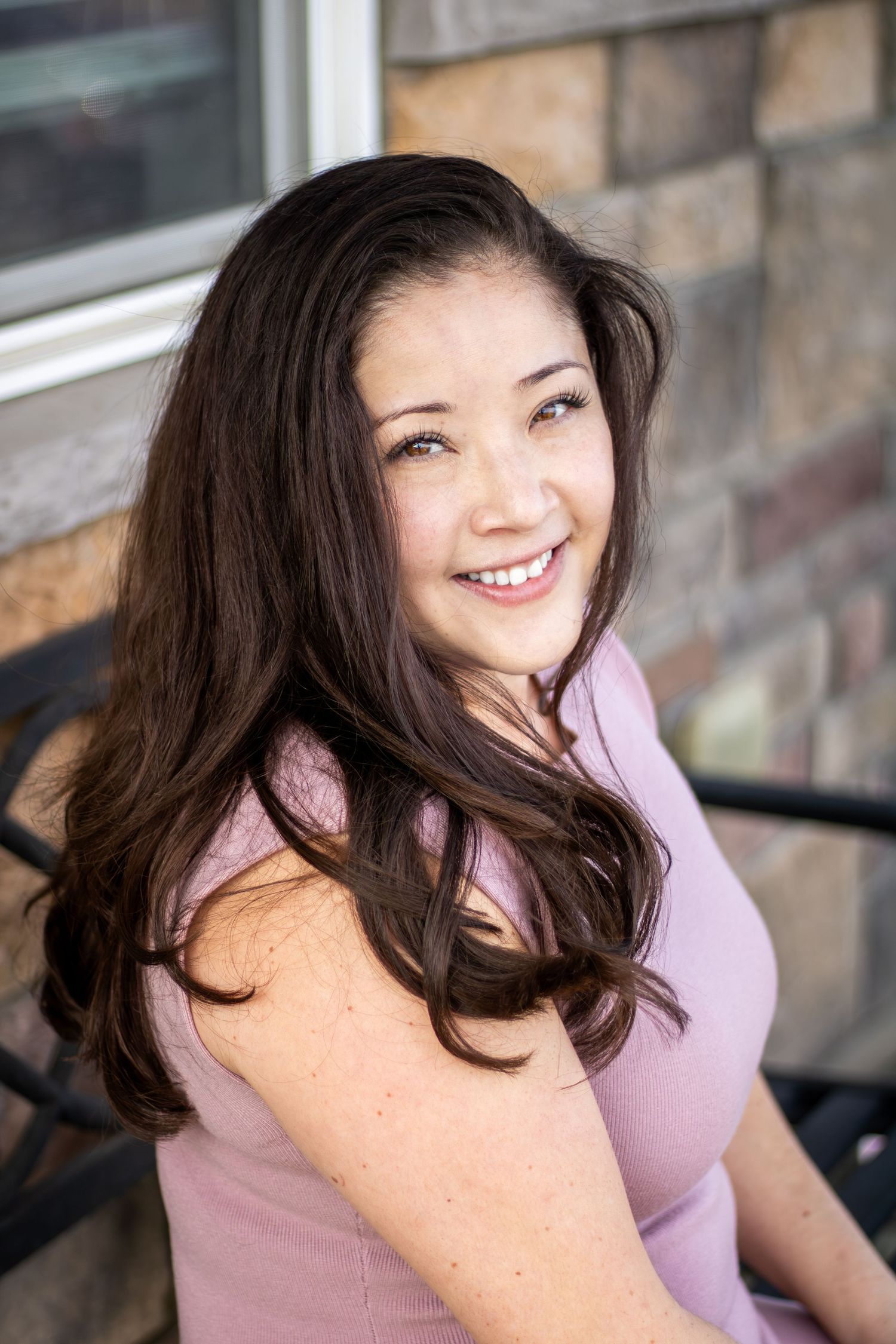 A series of candid shots showing someone in a lavender top with dark hair smiling and laughing against a brick wall.