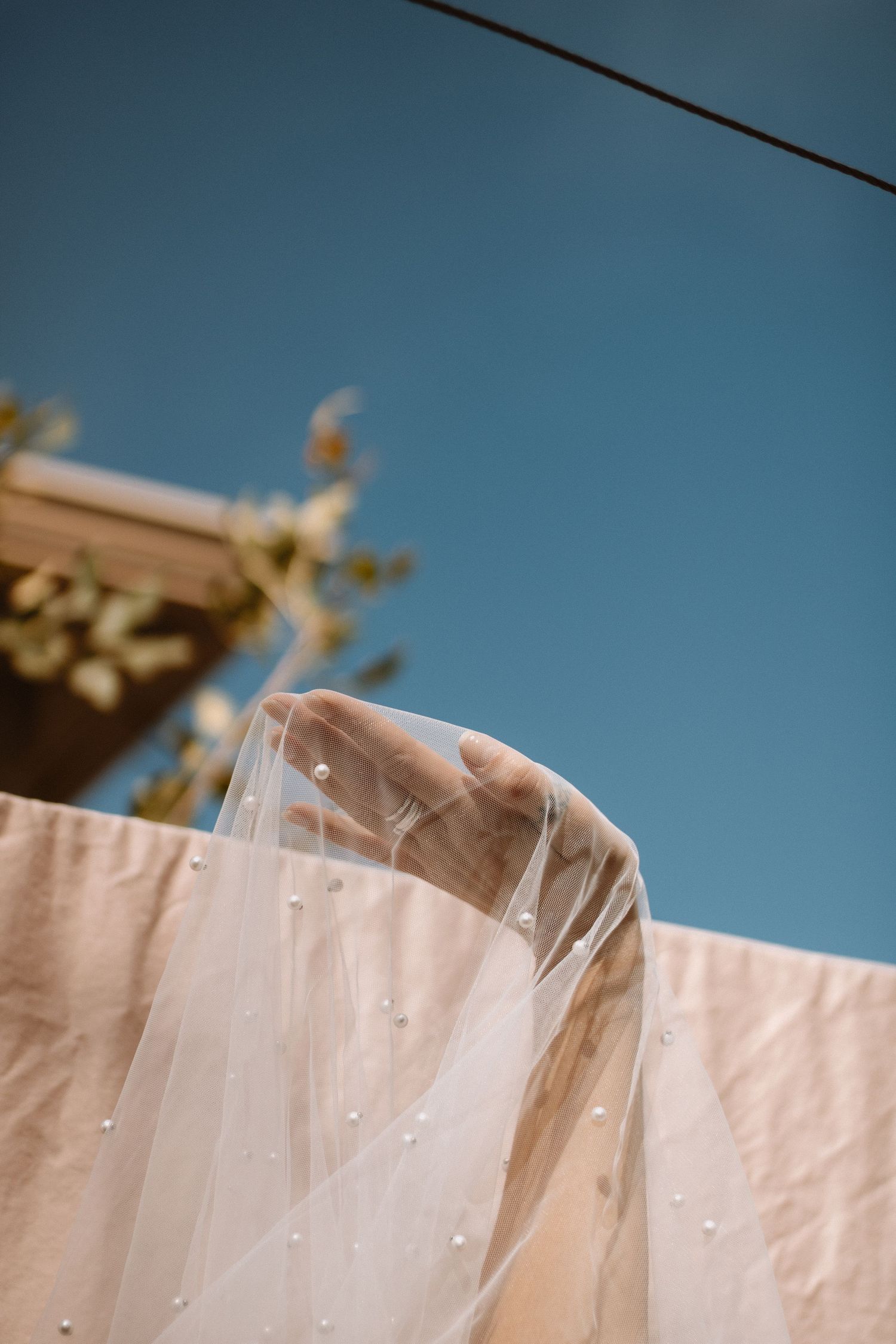 White sheets hanging on a clothesline against a bright blue sky on a sunny day.