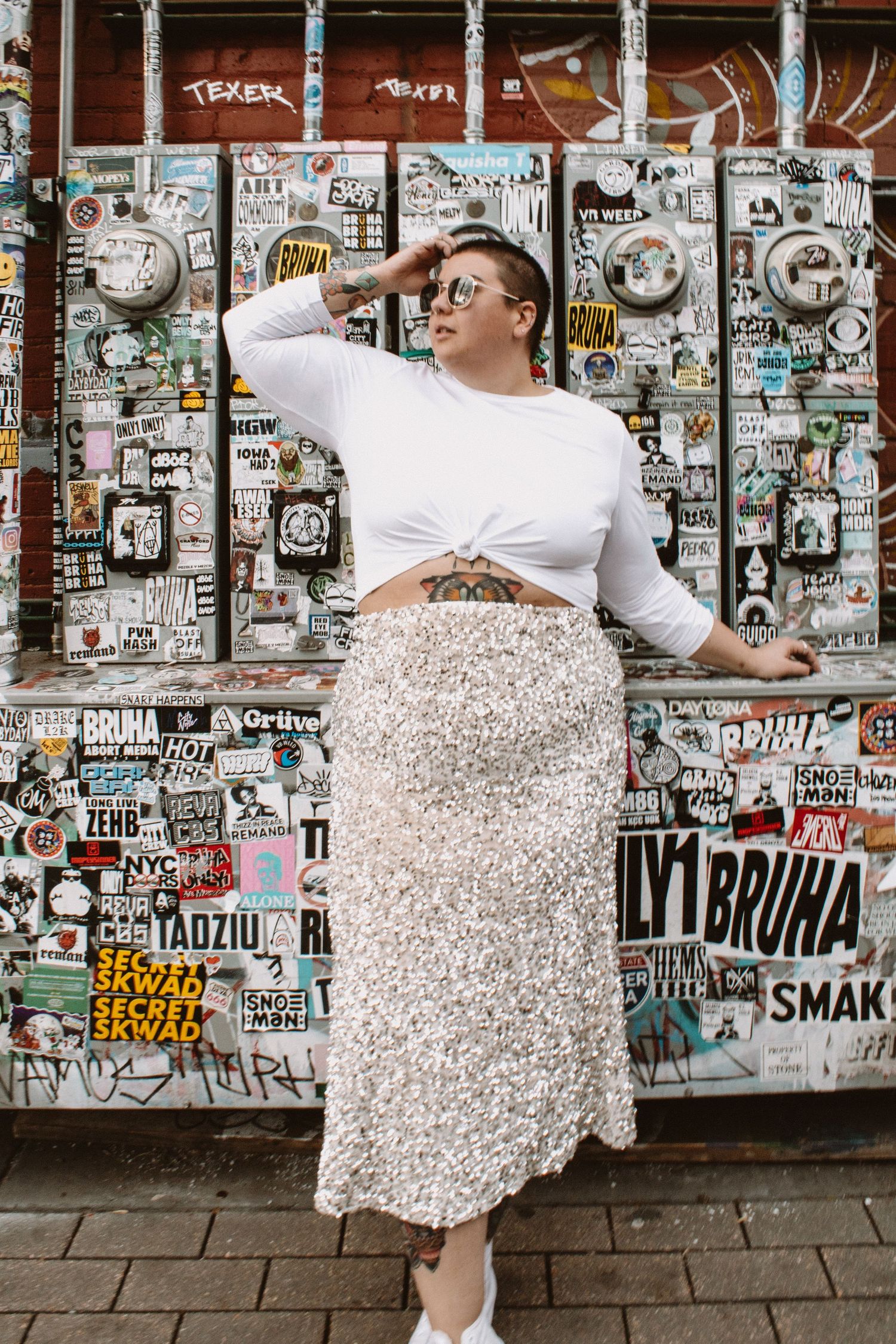 Person in white dress twirls against graffiti-covered wall in urban setting, creating artistic movement sequence.