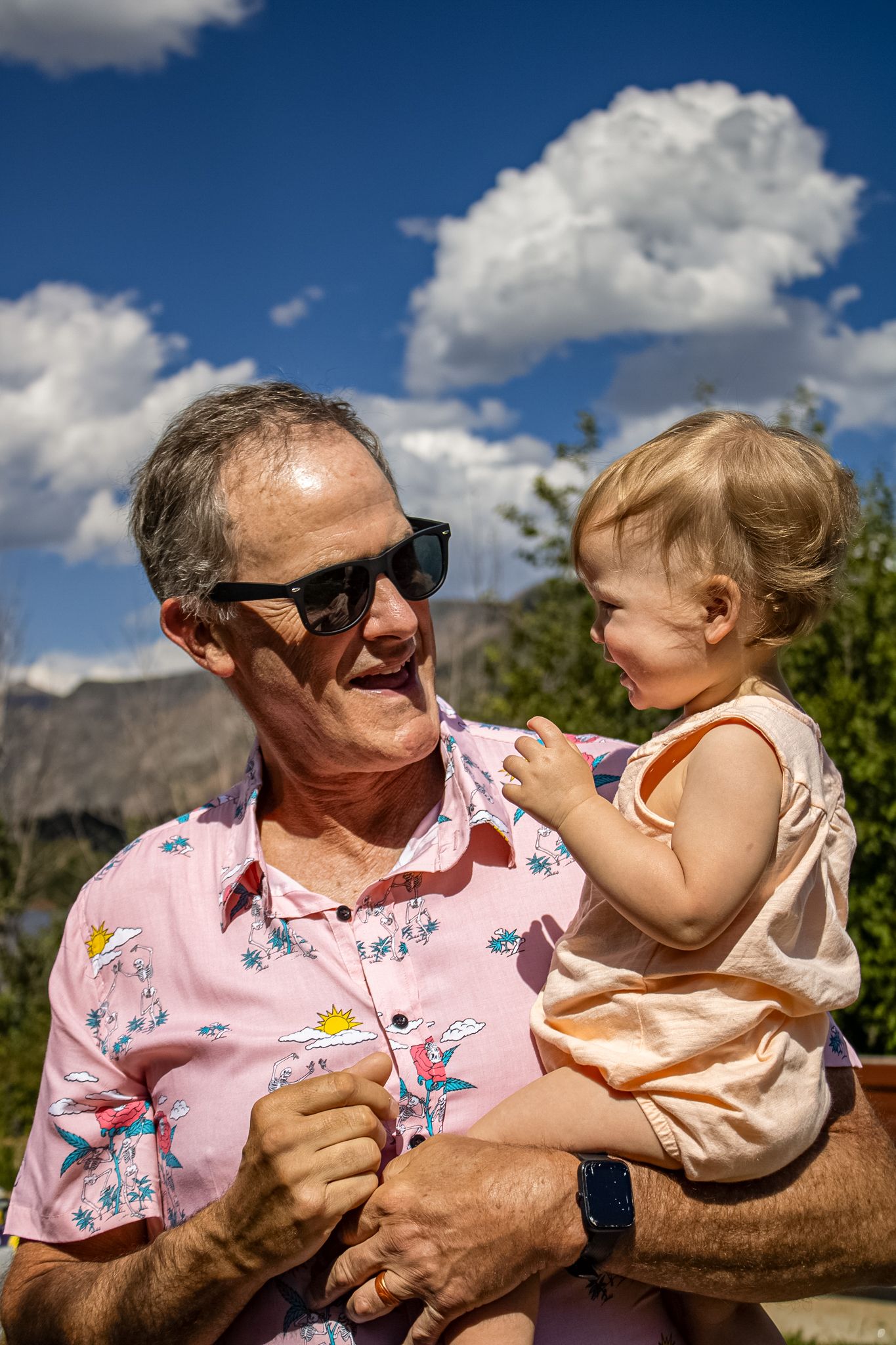 A series of outdoor photos showing playful interaction between a person in a pink floral shirt and a small child on a sunny day.