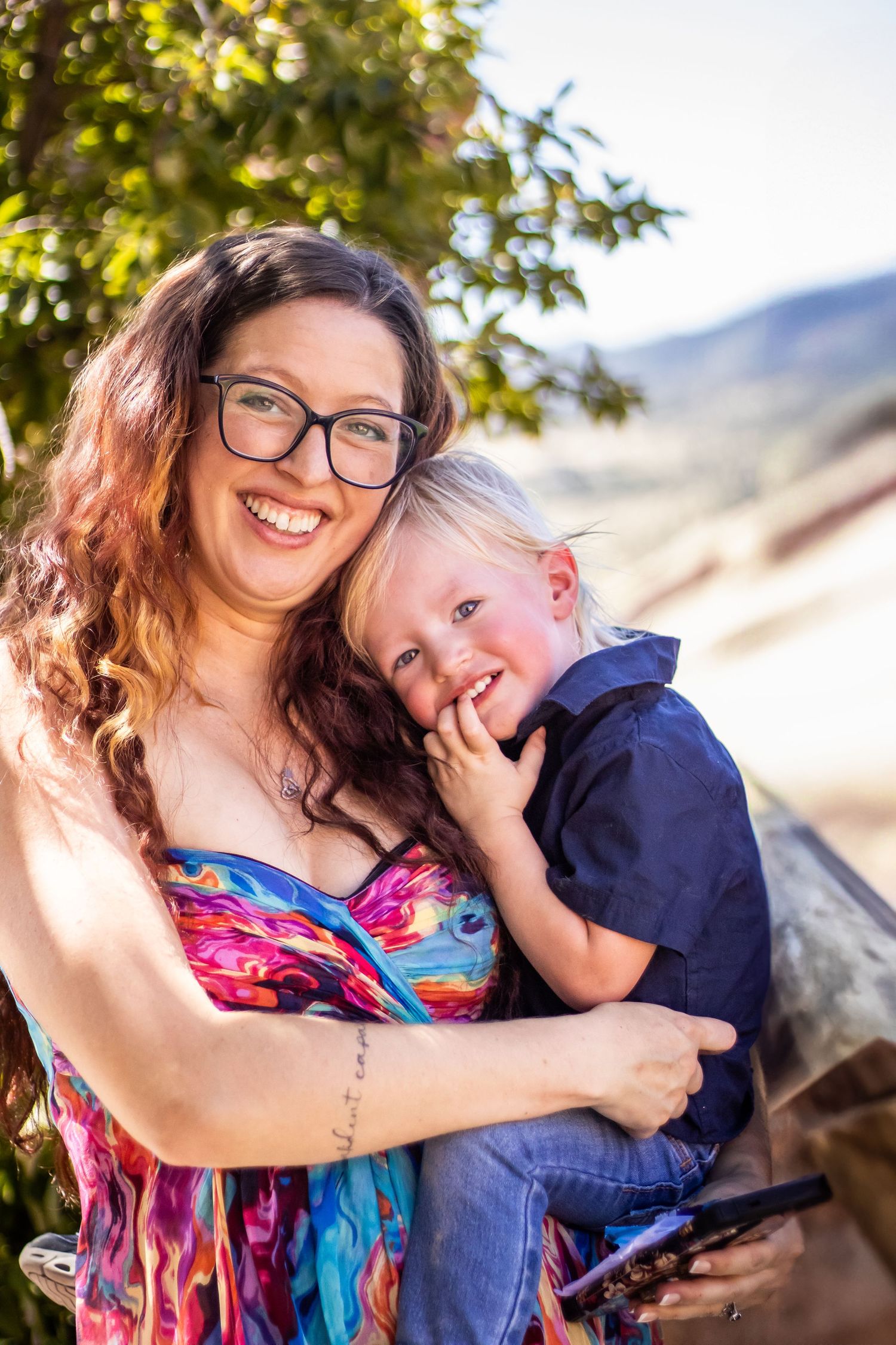 A joyful moment captured outdoors with a colorful floral dress and navy blue outfit against a sunny natural backdrop.