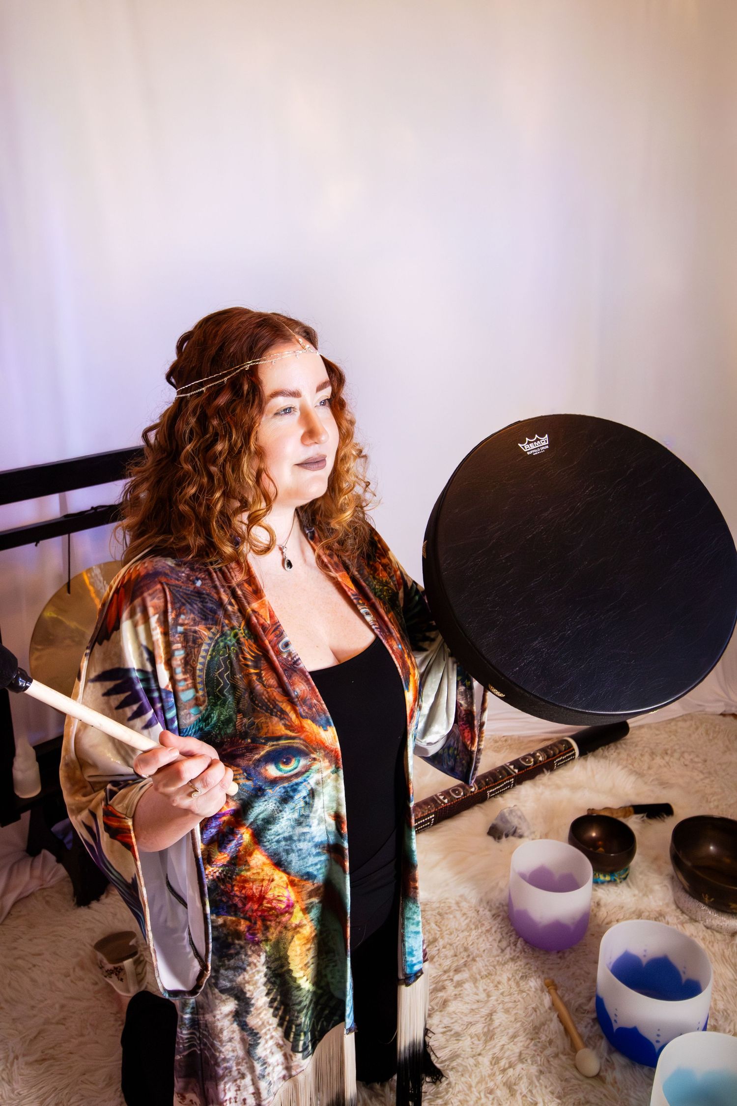 A musician performs with expressive energy in a colorful dress while playing drums in a studio setting.