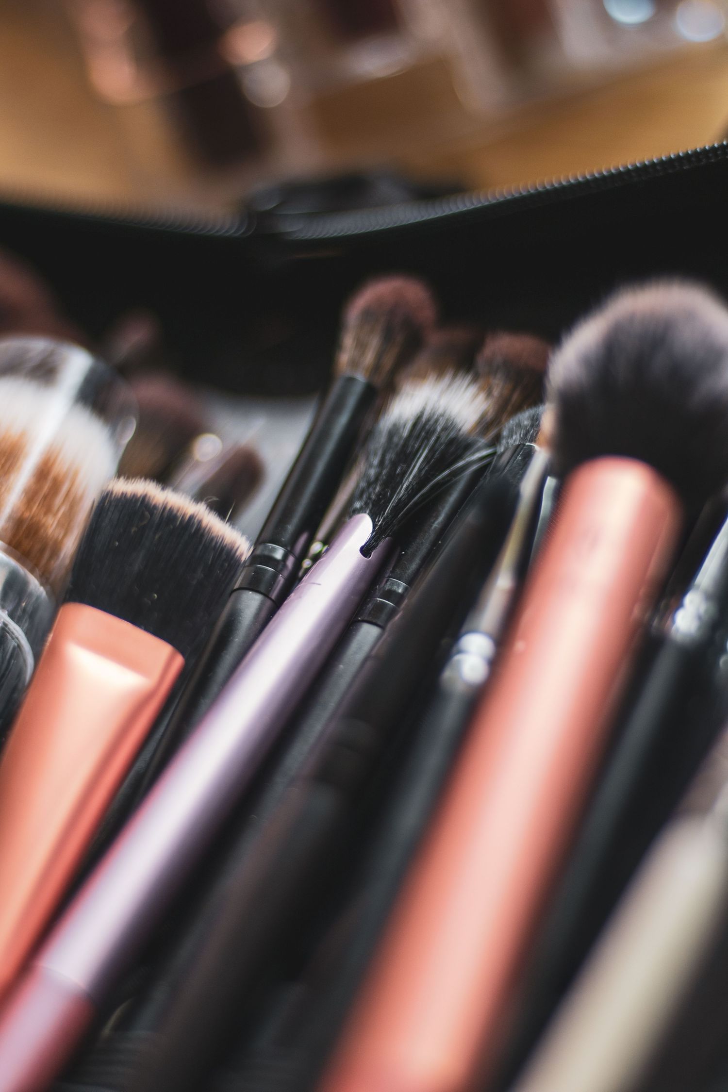 Collection of professional makeup brushes with pink and purple handles arranged in a black case.