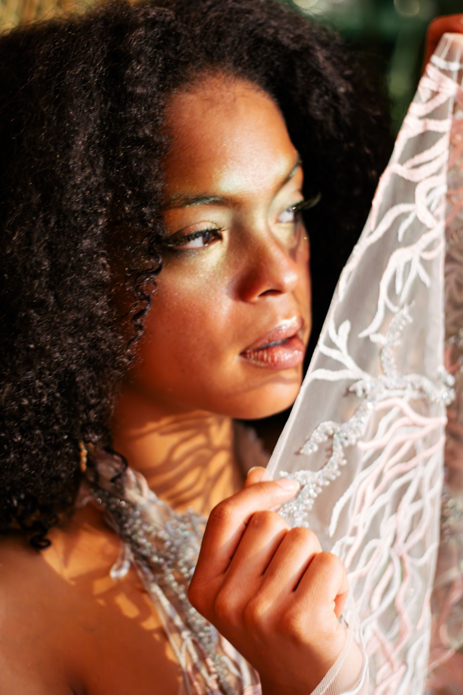 Artistic portrait sequence showing a person in dramatic side lighting with natural curly hair against a white lace background.