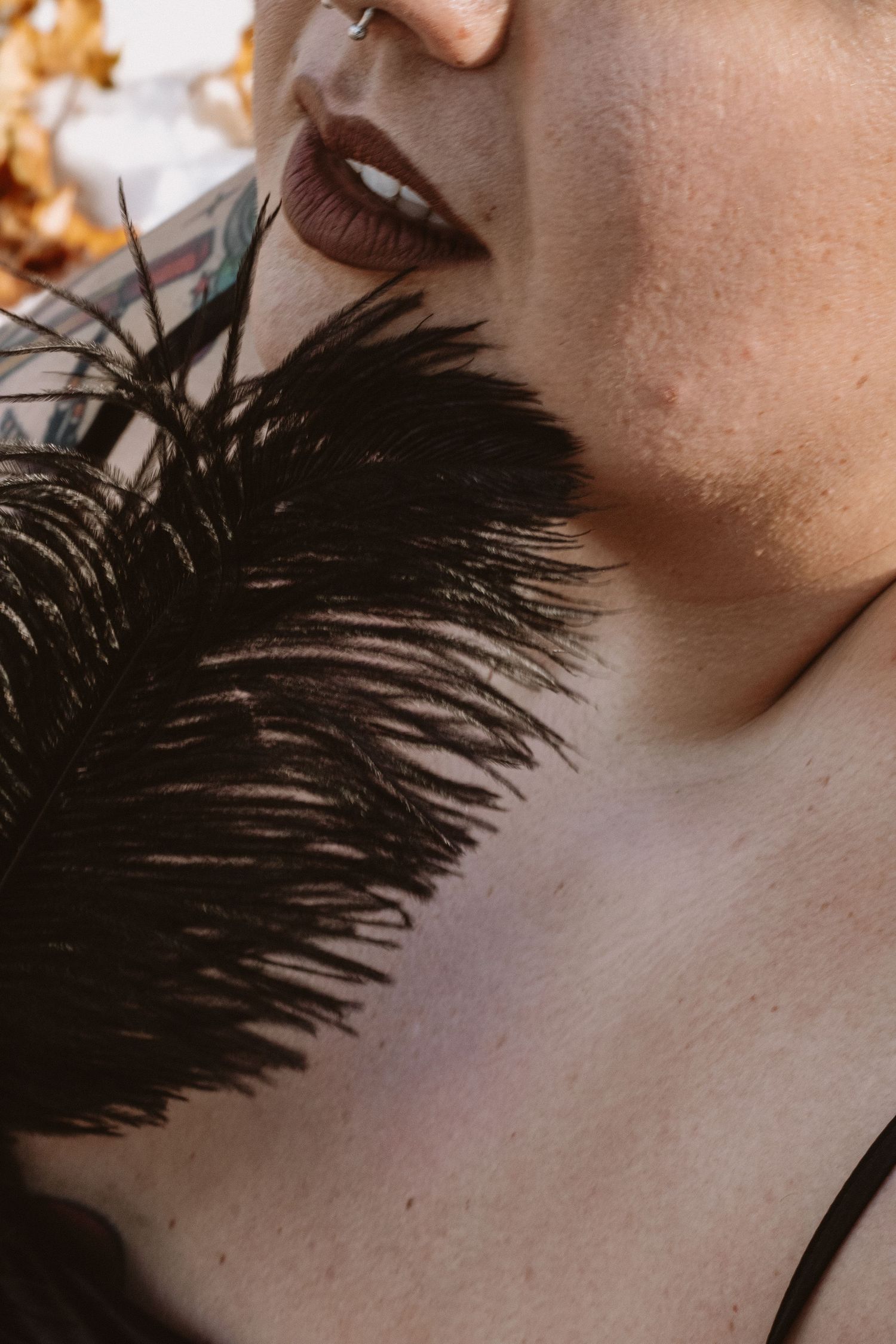 A close-up sequence showing a black feather gently brushing against skin in an artistic manner.