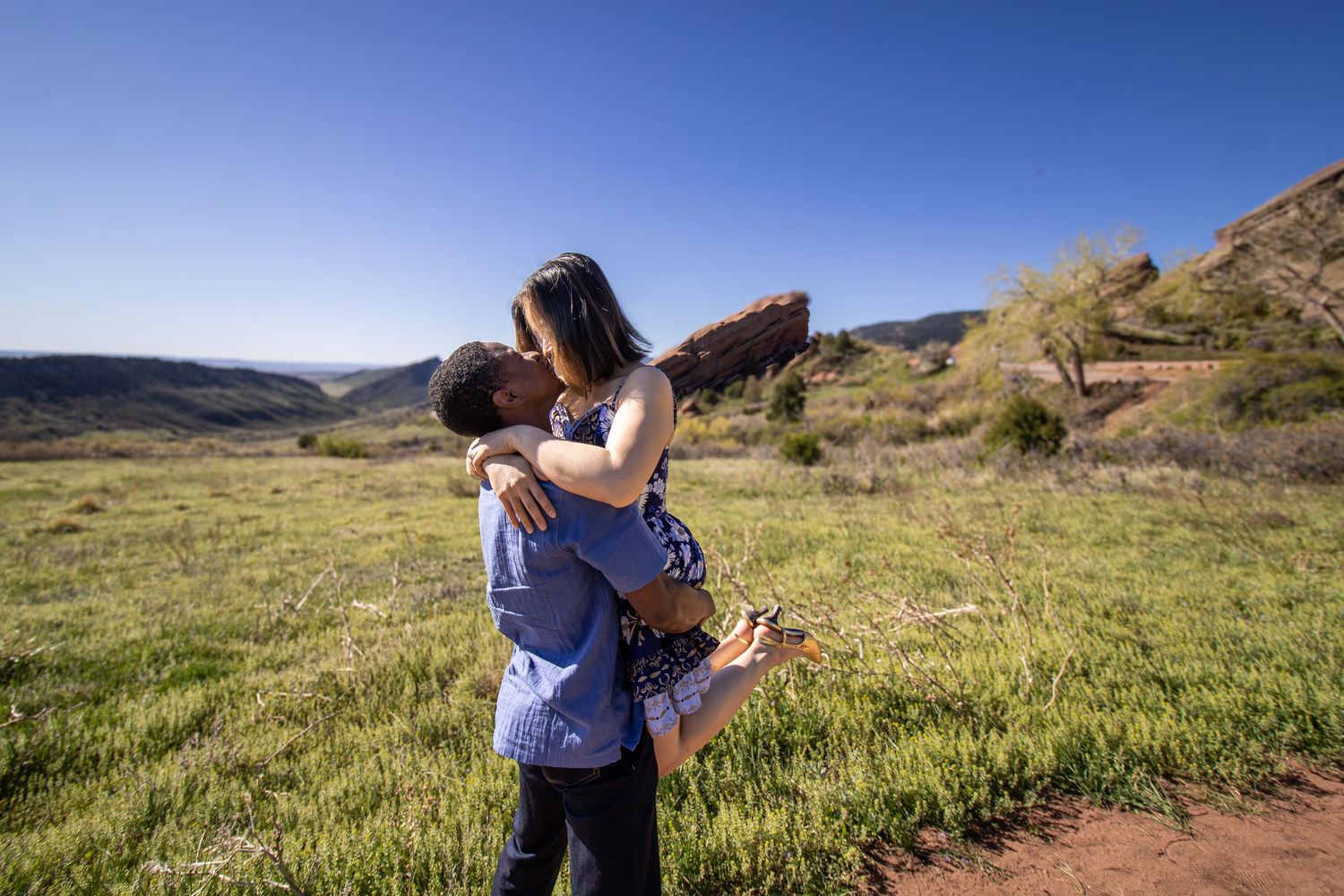 A couple embraces in a scenic mountain meadow at Red Rocks Park, Colorado on a sunny day.