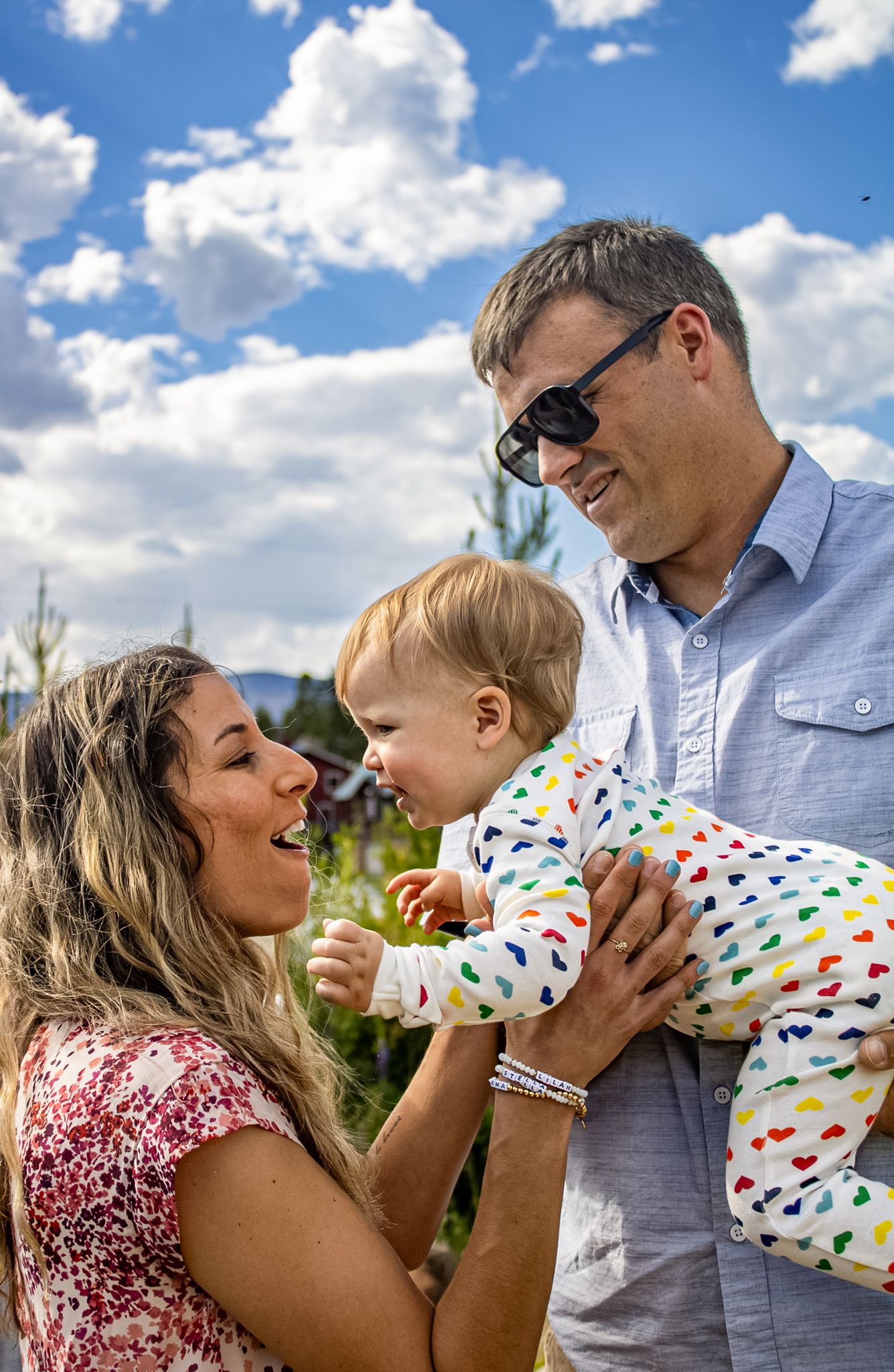 Sweet candid moments between family members playing and laughing together outdoors on sunny day.
