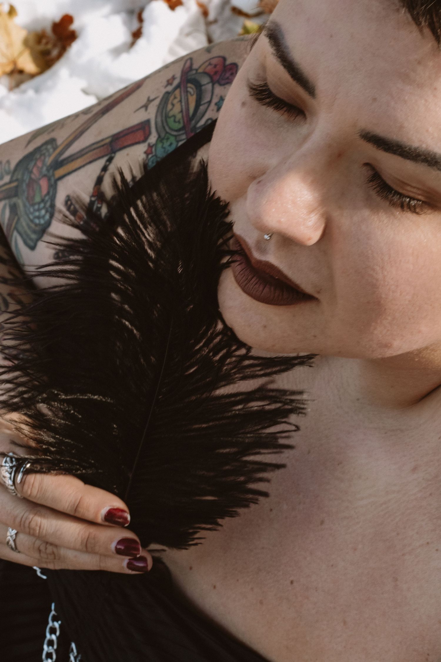 A series of artistic portraits showing dark feathers against pale skin in a dramatic fashion editorial style.